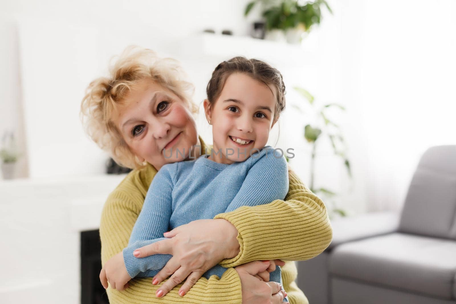 Portrait of happy old grandmother and kid girl looking at camera, smiling grandma with granddaughter making video call, child and granny vloggers recording video blog or vlog together