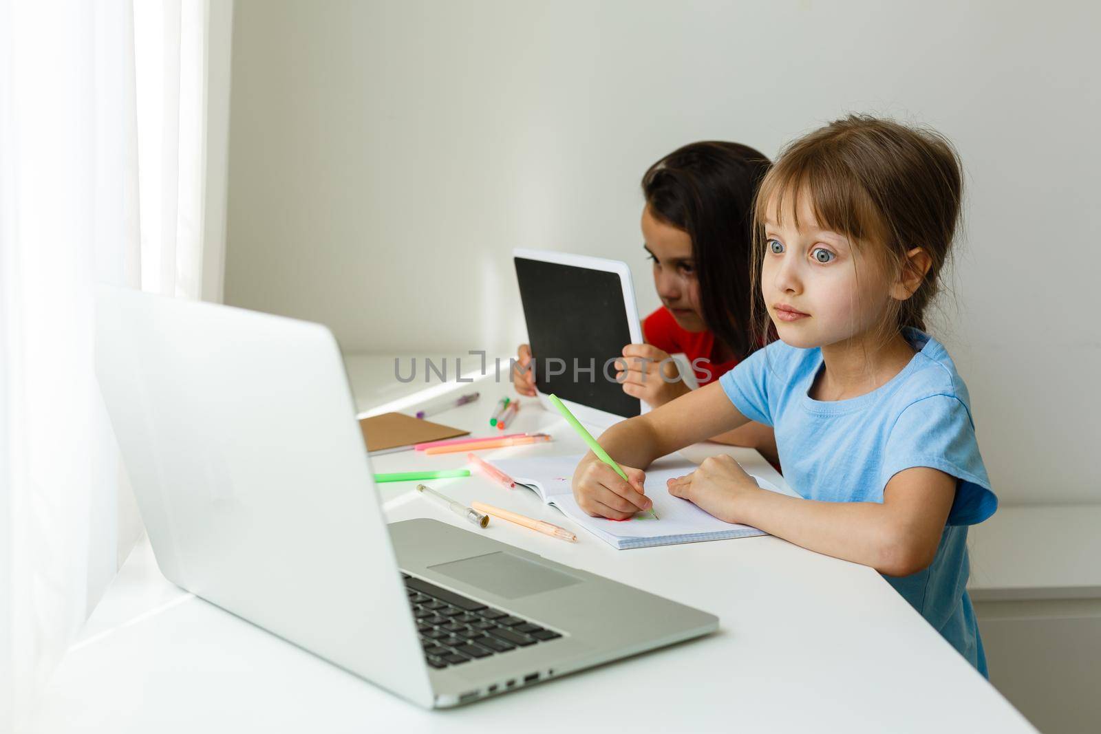 Pretty stylish schoolgirls studying during her online lesson at home, social distance during quarantine, self-isolation, online education concept