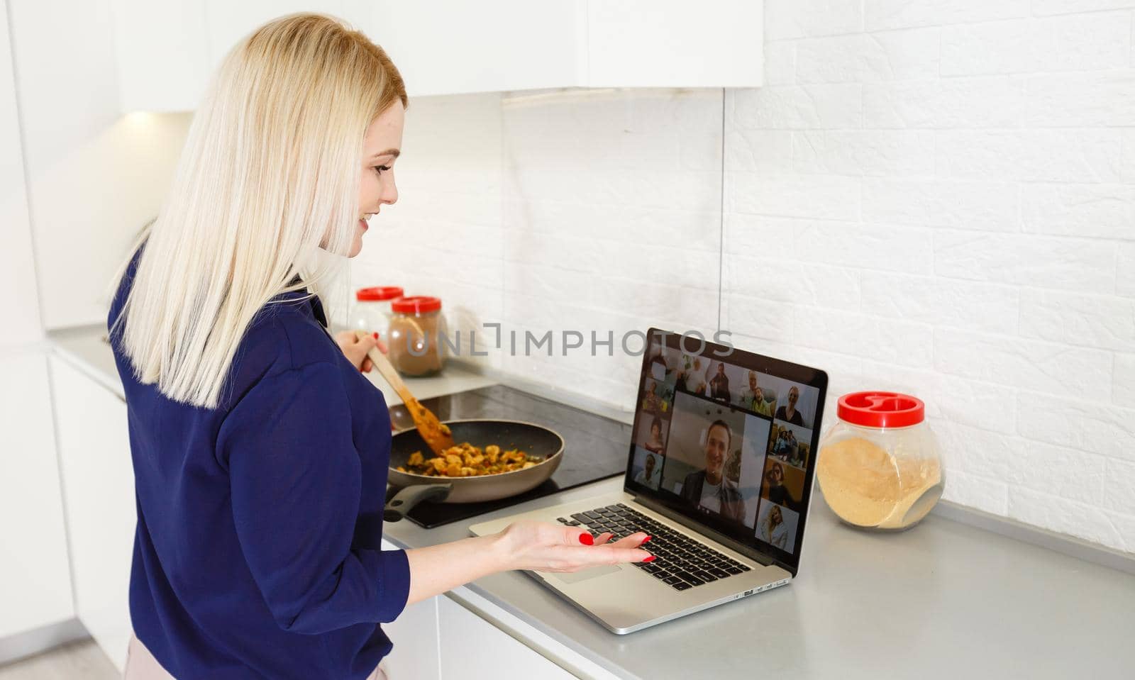 Beautiful girl is learning to cook healthy food online by the internet from a laptop in gray kitchen on table.
