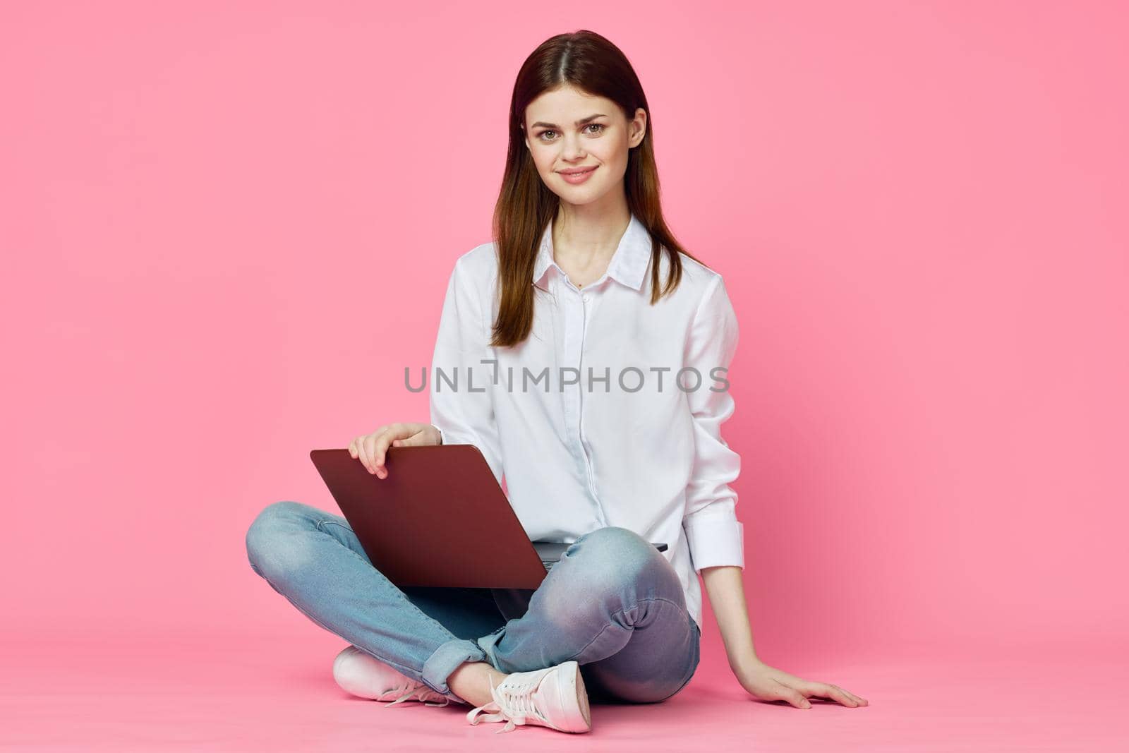 woman sitting on floor with laptop shopping entertainment pink background. High quality photo