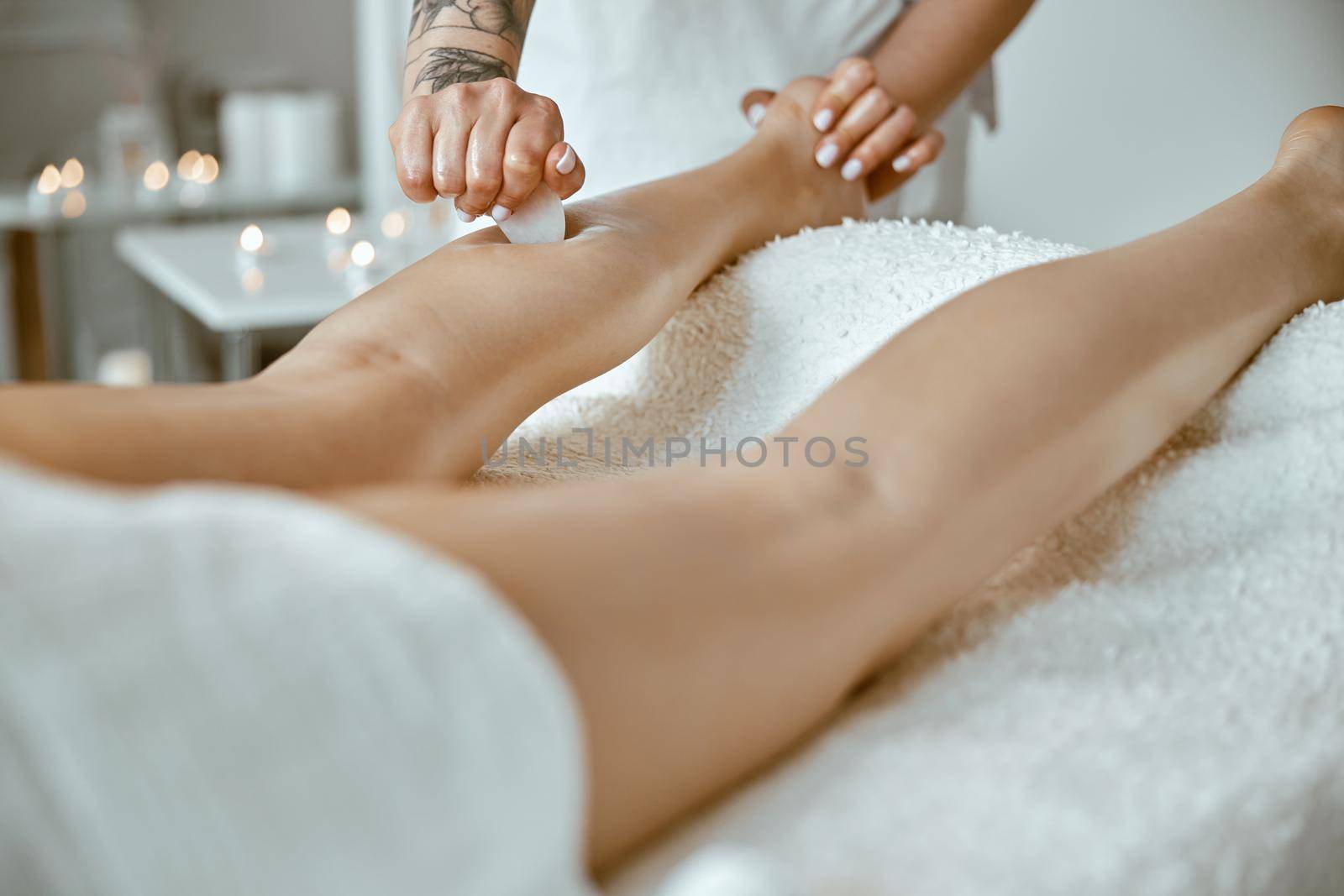 Massagist woman is doing professional leg massage in modern salon