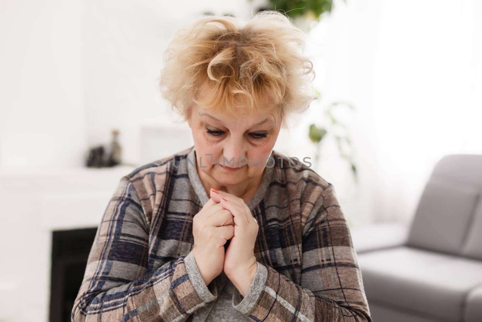 Religious faithful middle aged woman praying with hope faith holding hands clasped together in namaste at home in morning, old mature lady believer christian saying worship prayer by Andelov13