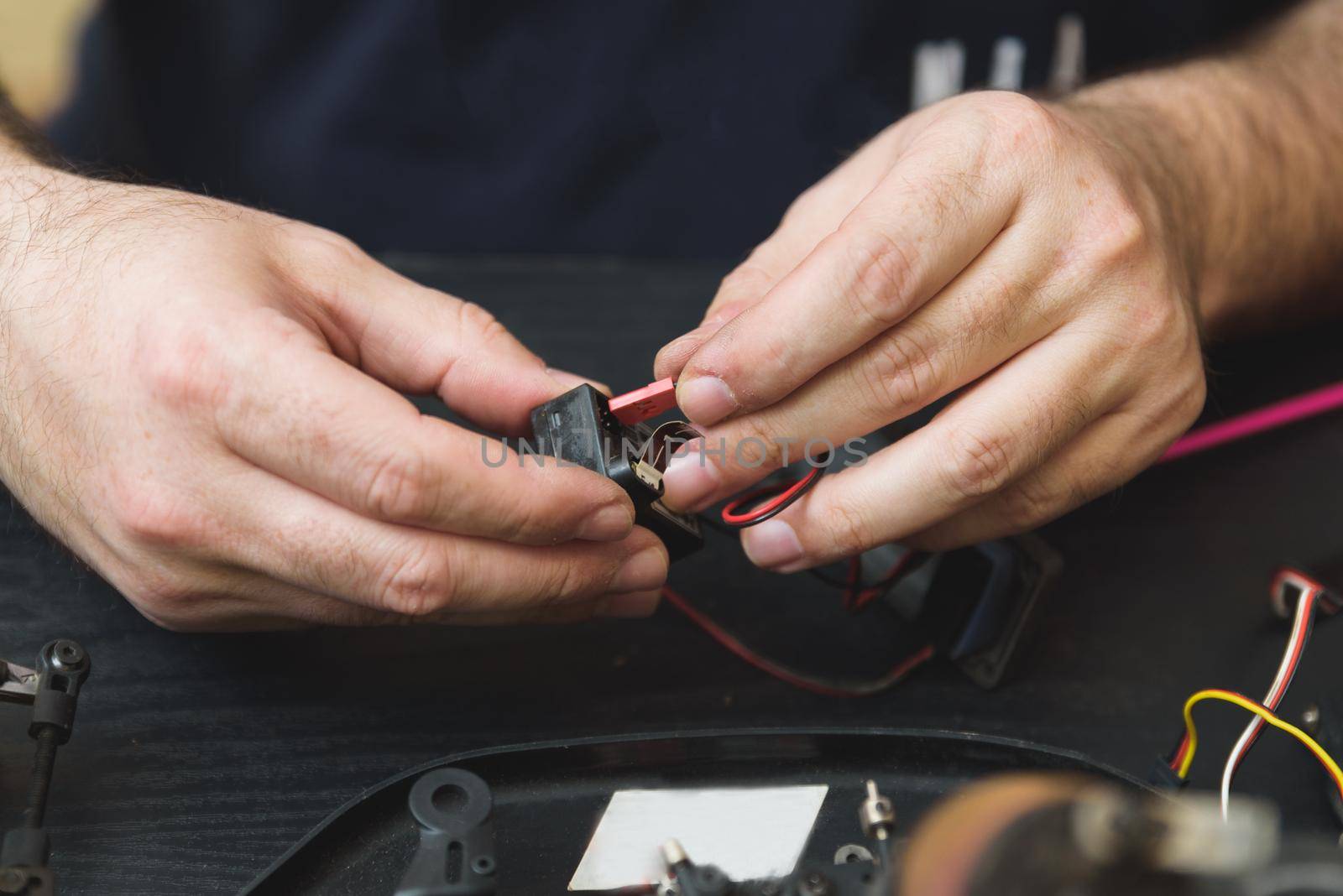 Young Caucasian male assembling toy RC car at home in the evening.