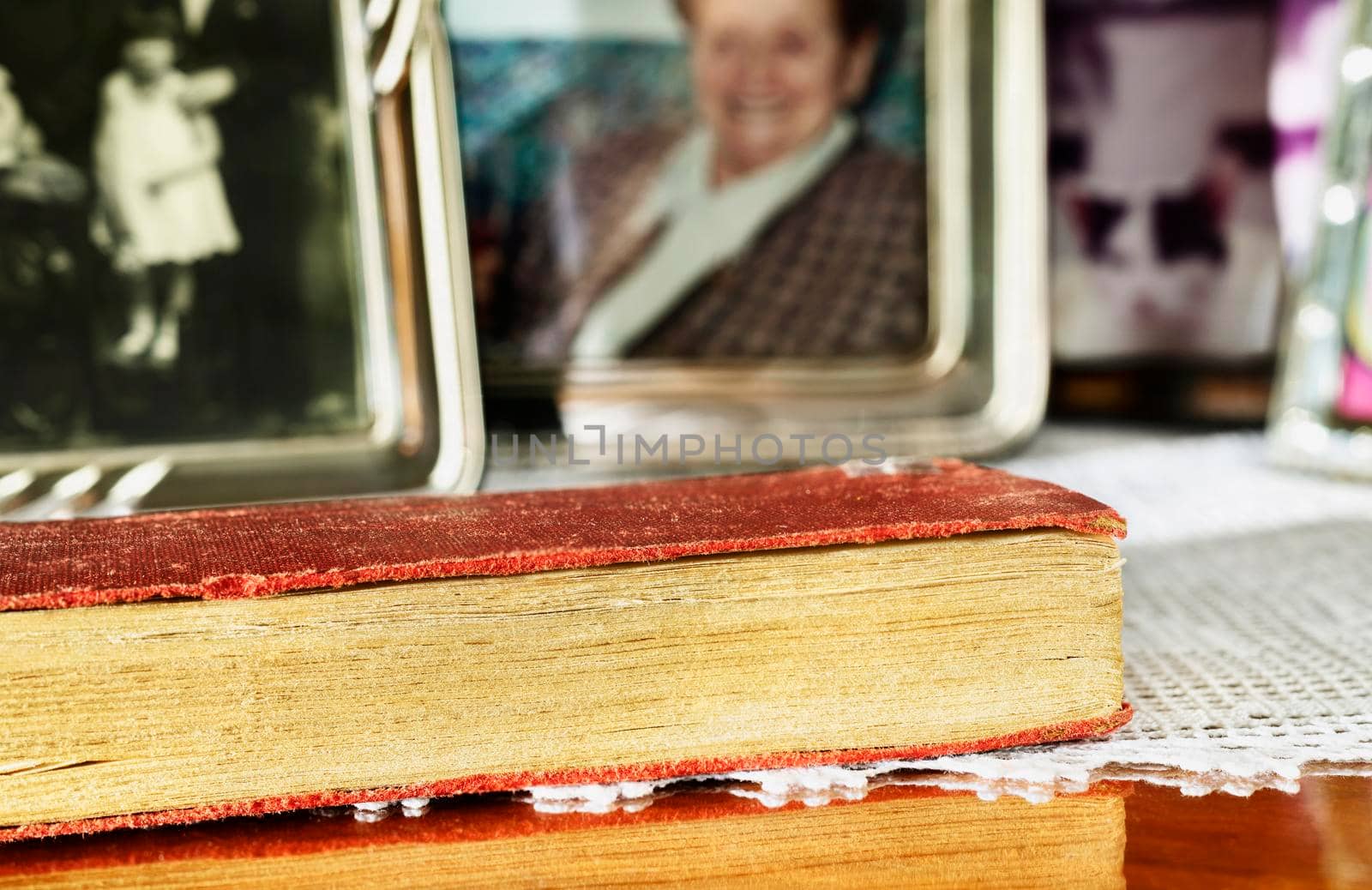 Old book with red cover on wooden table , in the background photos in photograph holder