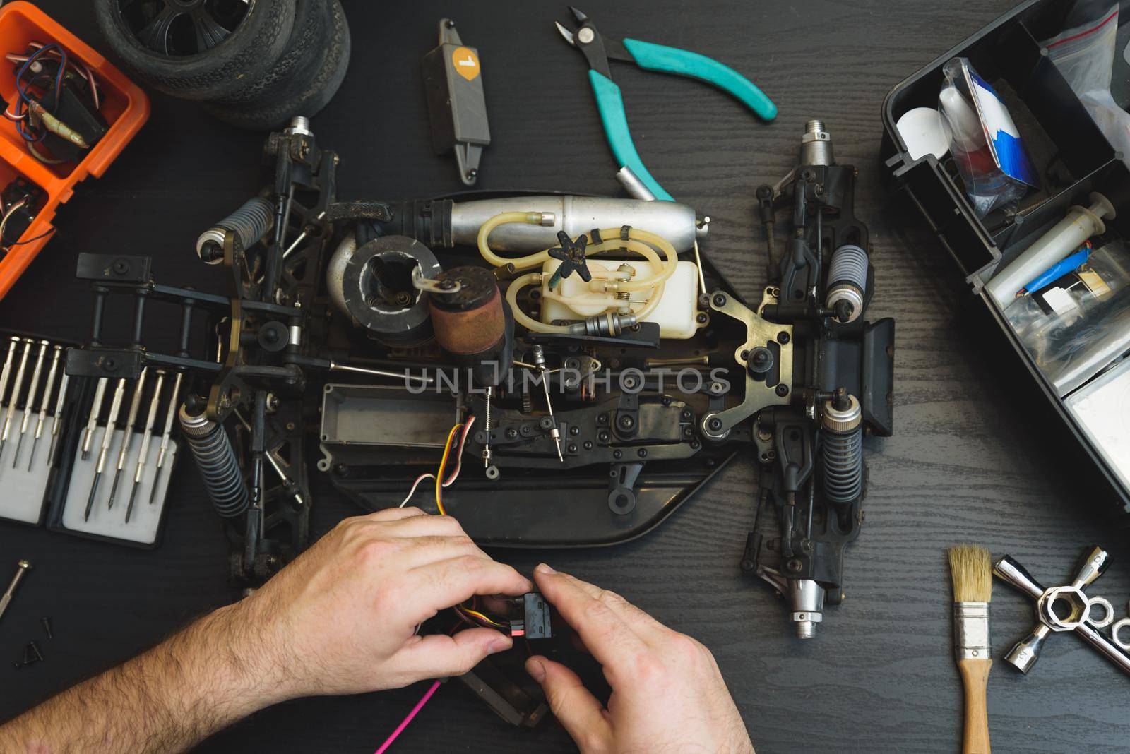 Young Caucasian male assembling toy RC car at home in the evening by jcdiazhidalgo