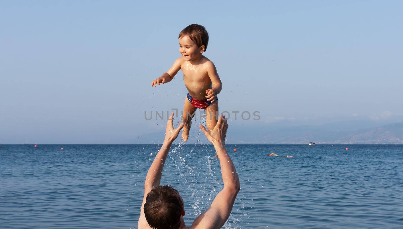 Happy family and healthy lifestyle. A young father teaches a child to swim in the sea