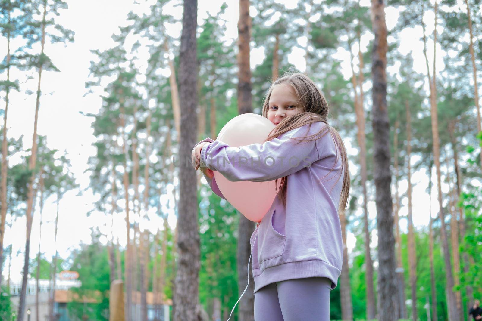 pretty girl tween teenager in purple costume having fun playing with hot air pink balloon outdoors. holliday, party, birthday, celebration. happy children.