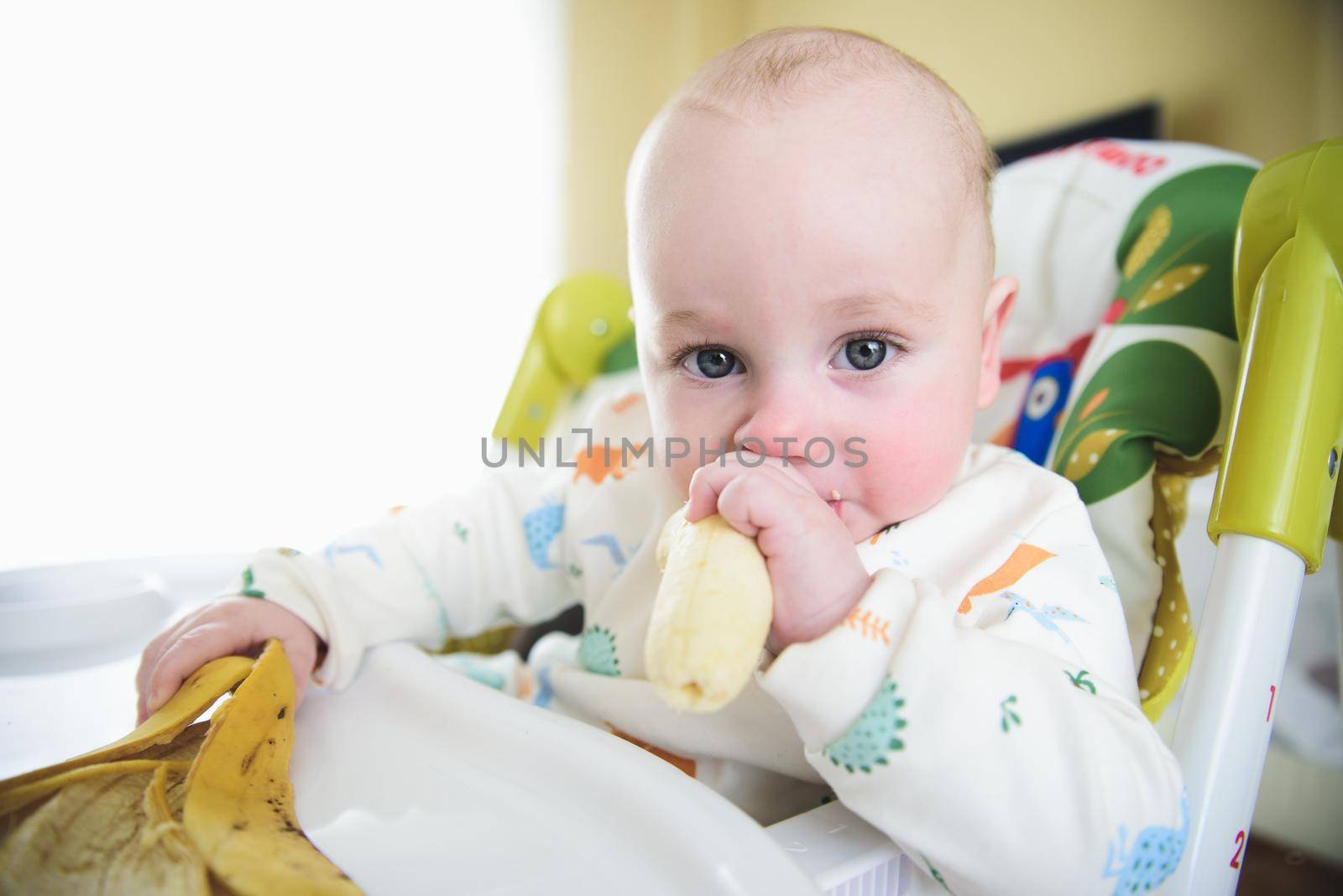 baby sitting in his chair eating banana.