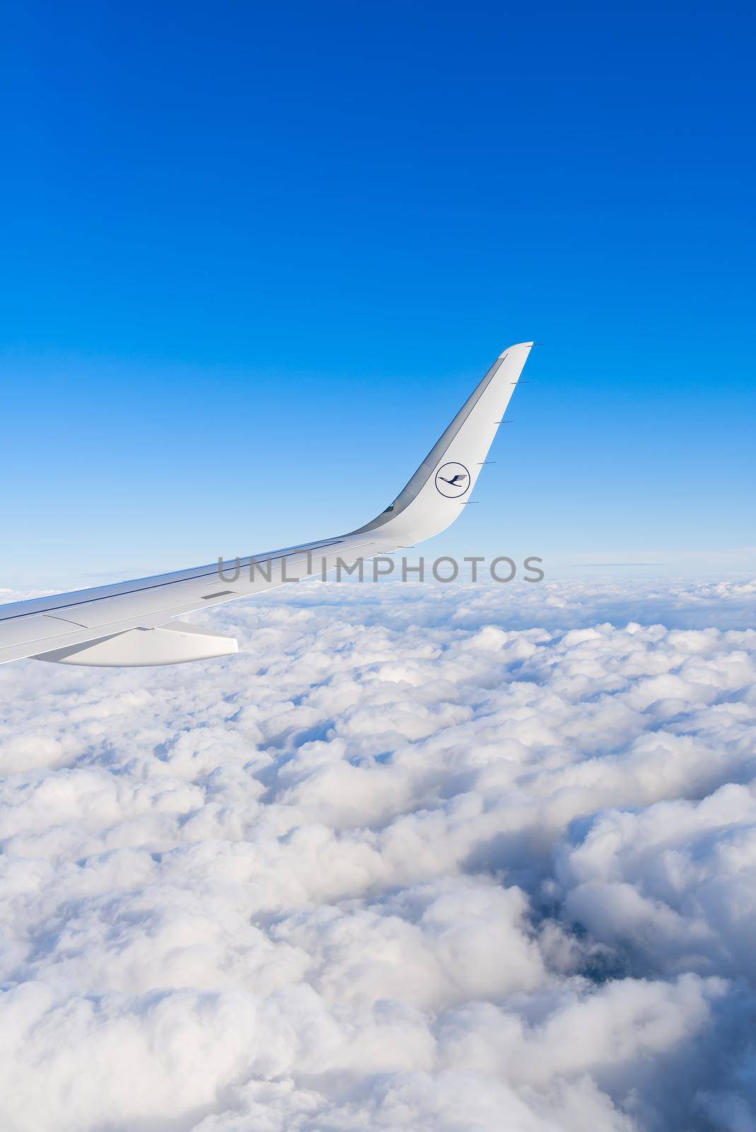 22.05.2021 Frankfurt, Germany - The Airbus A321 wing with Lufthansa airline logo and blue sky over clouds background. airplane wing in sunny day
