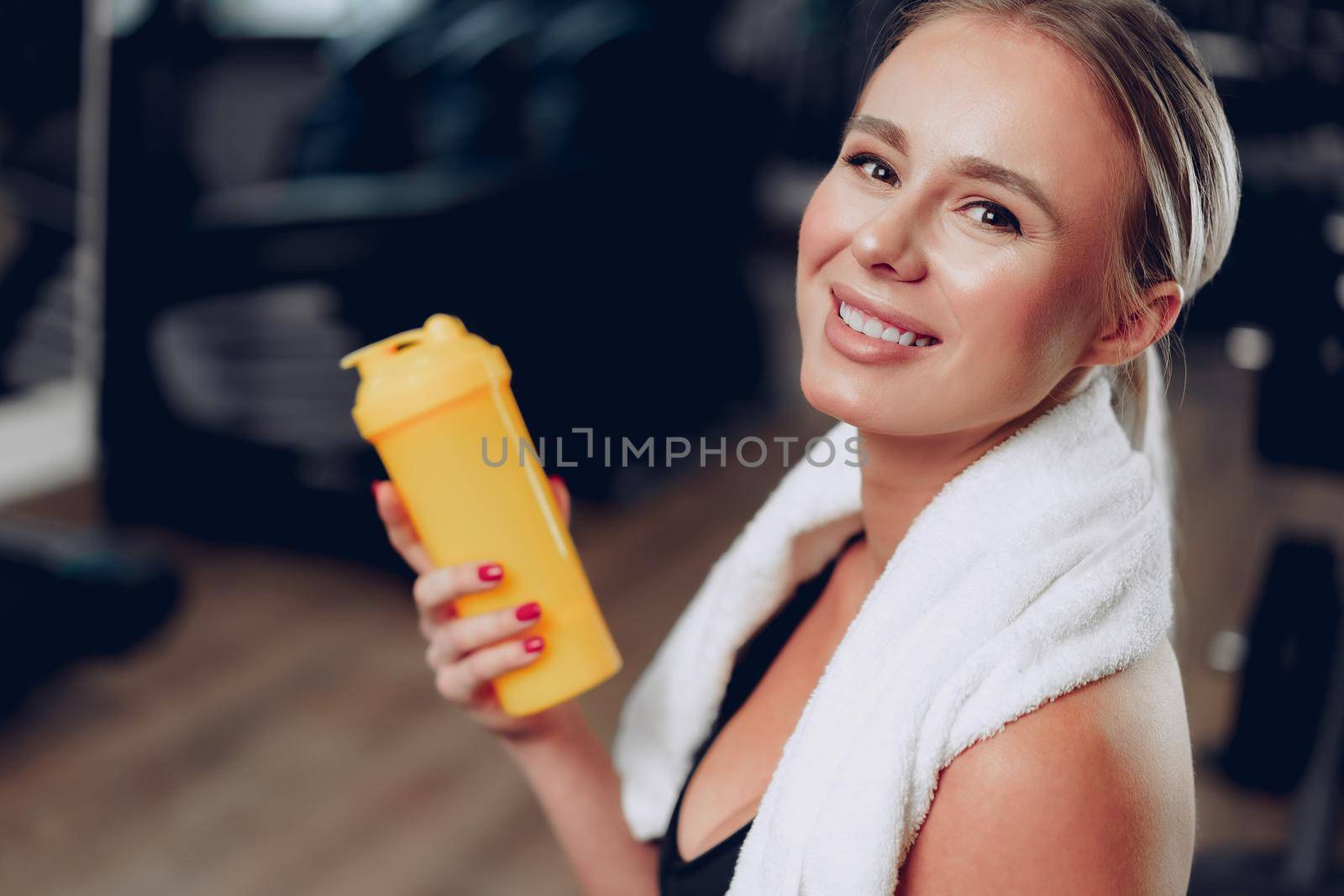 Young sporty woman having a drink in a gym after workout, close up