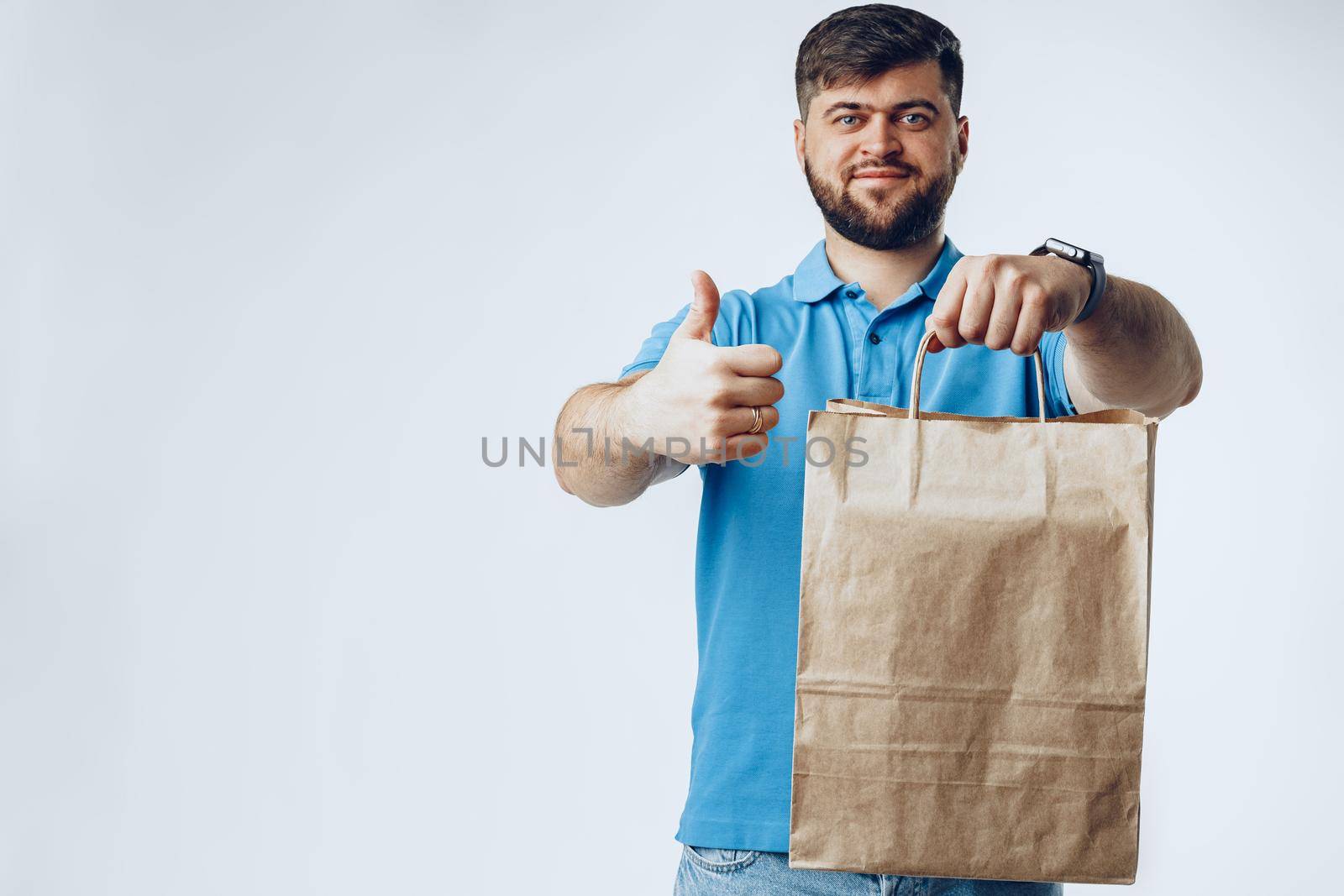 Delivery man with bag order from groceries on grey background by Fabrikasimf