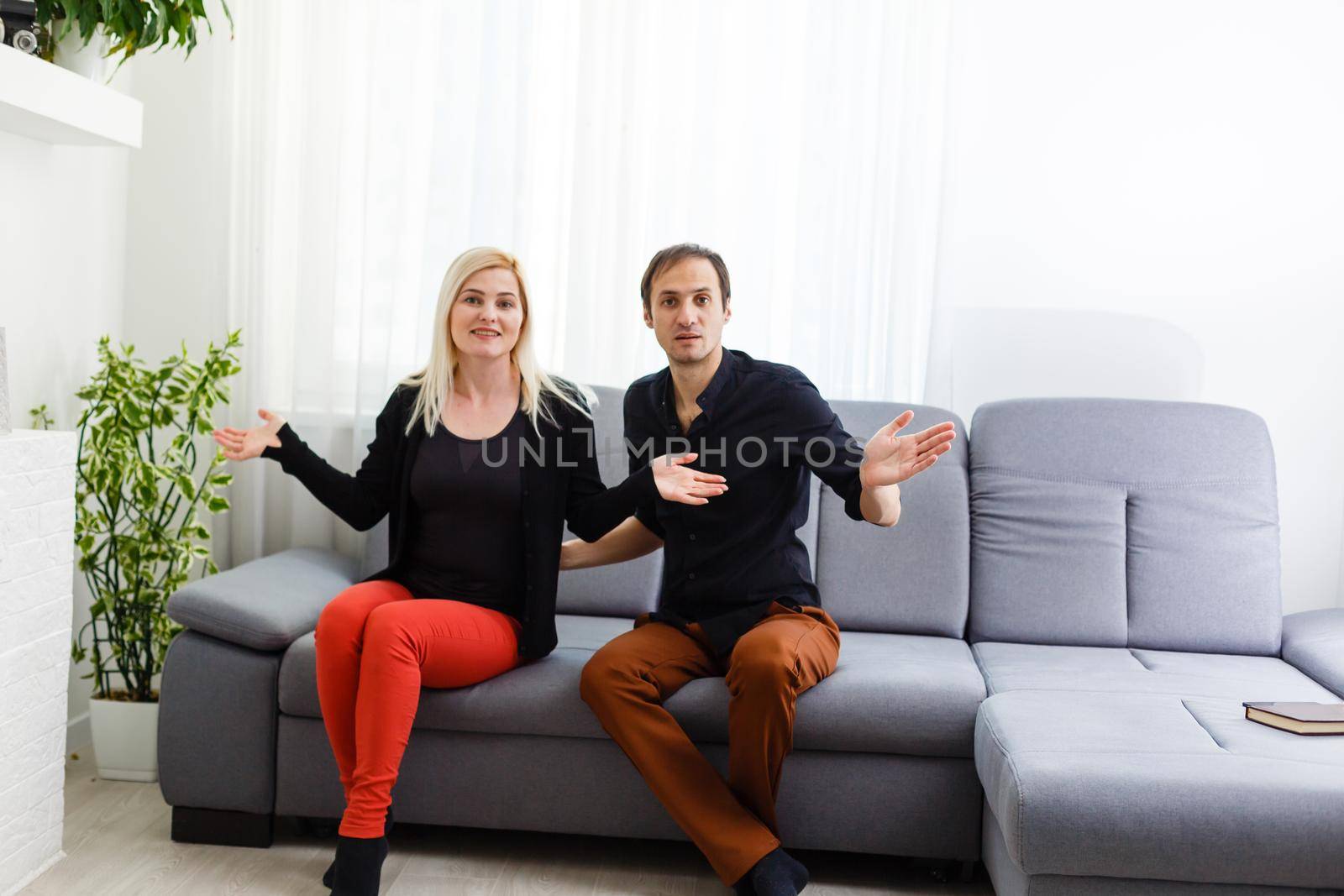 Happy young couple is hugging and smiling while sitting on the couch at the psychotherapist.