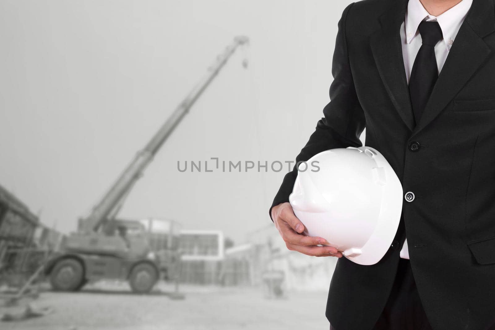 engineer holding white helmet with construction crane background
