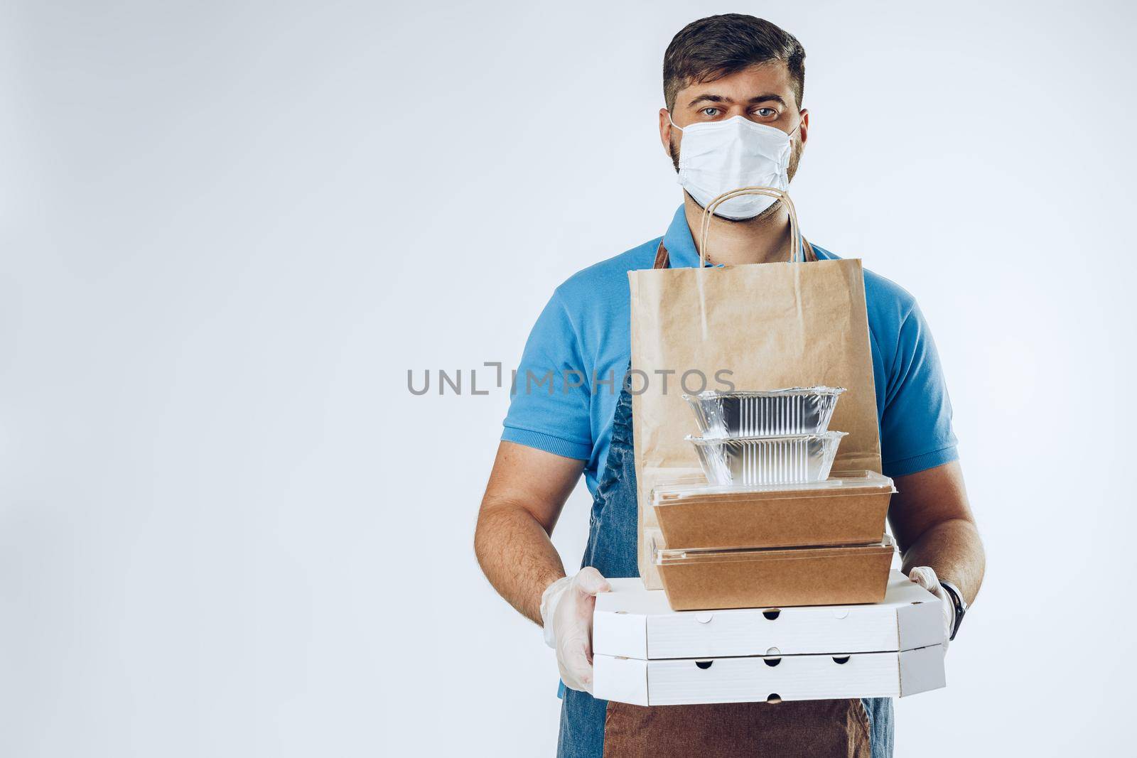 Delivery man in protective mask and medical gloves holding takeaway food. Compliance with the hygiene rules while covid-19 pandemic. Safe service