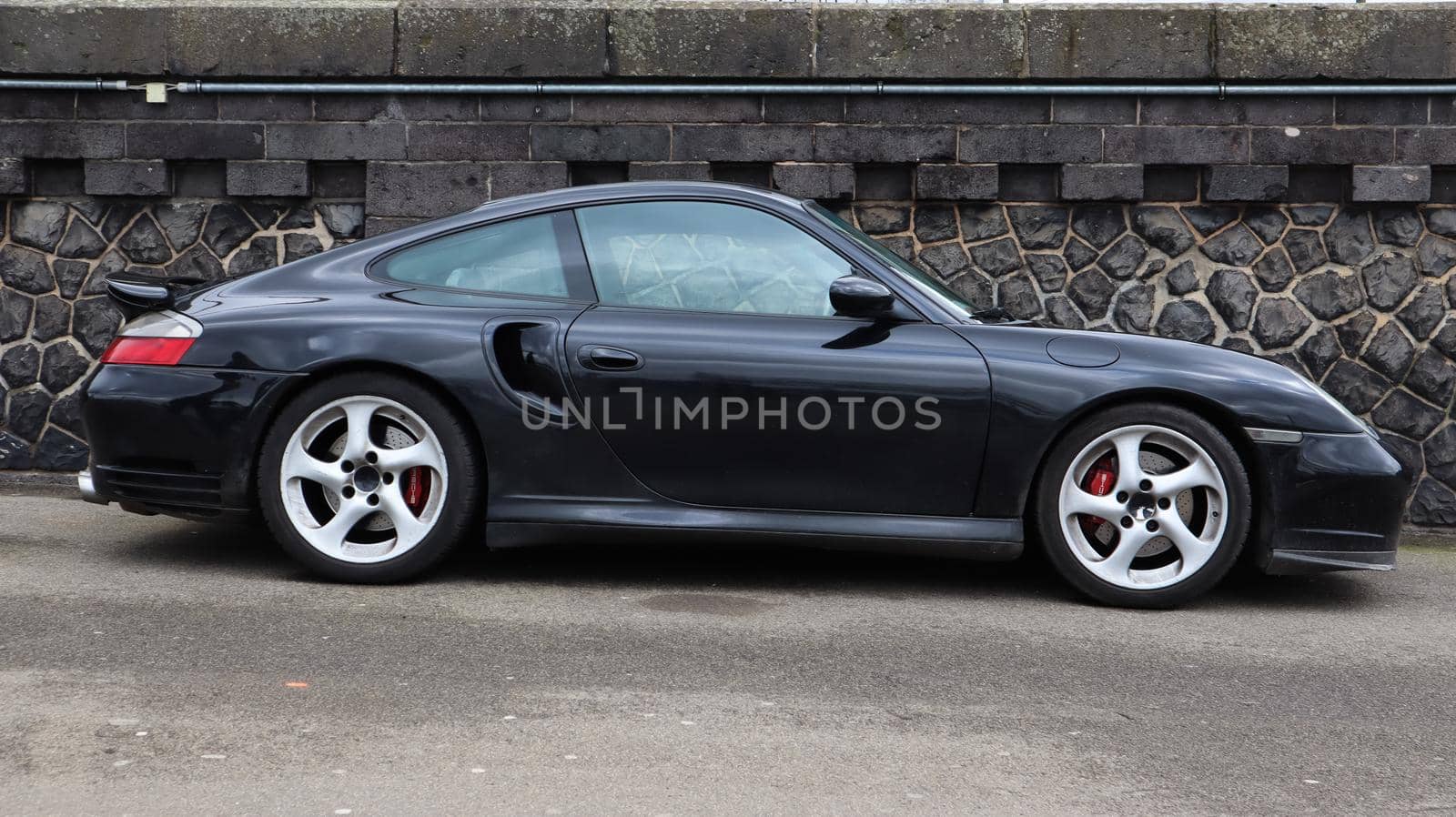 Dusseldorf, Germany - February 28, 2020: side view of a black Porsche 991 car parked on the street. Second generation car. German car manufacturer founded by renowned designer Ferdinand Porsche.