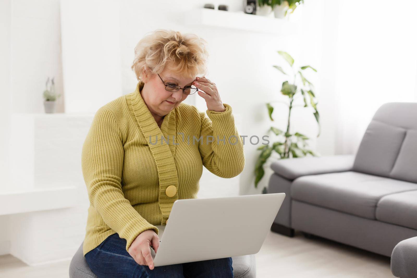 Old woman working on laptop computer at home, Grandma using notebook and searching on internet site