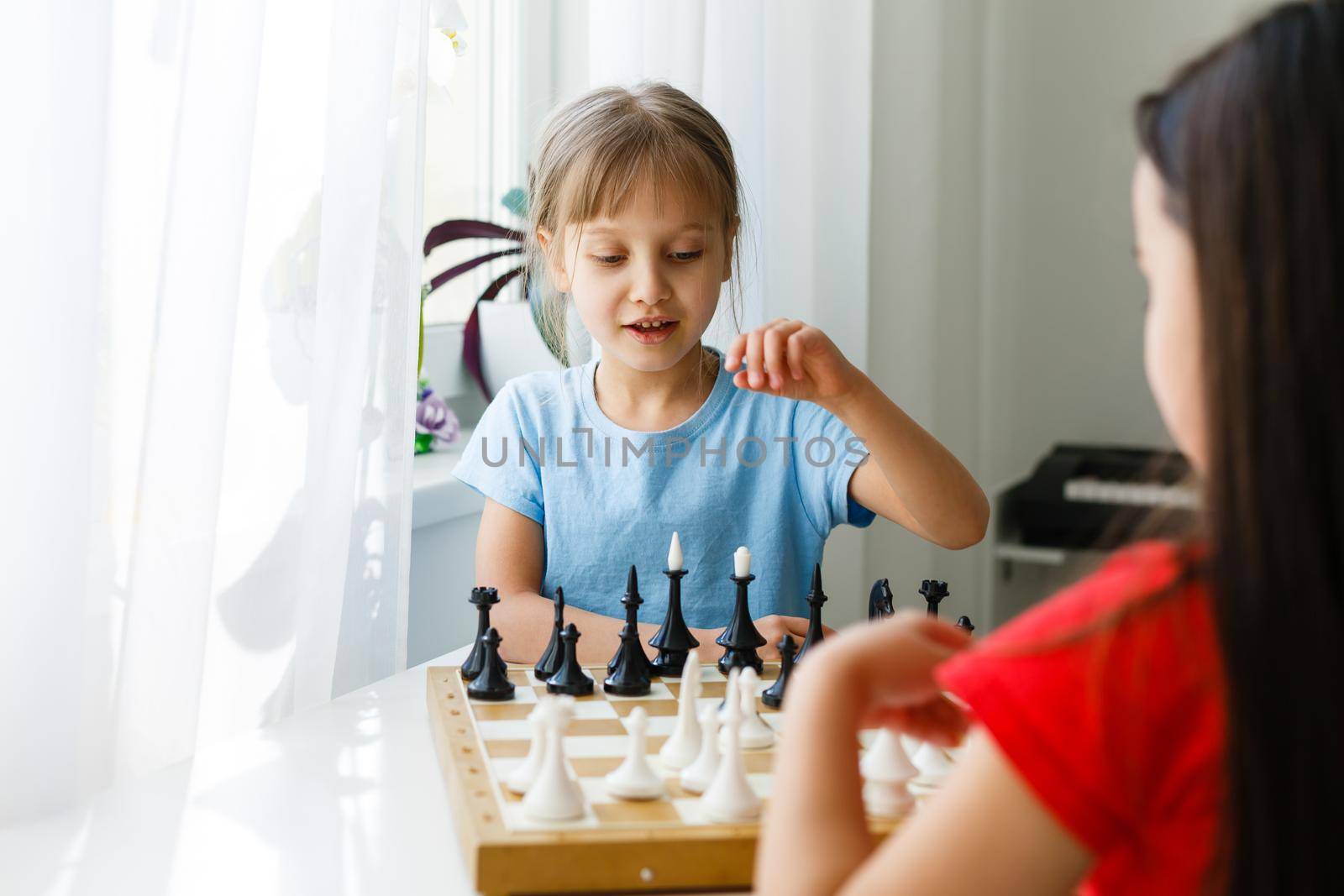 Two cute children playing chess at home