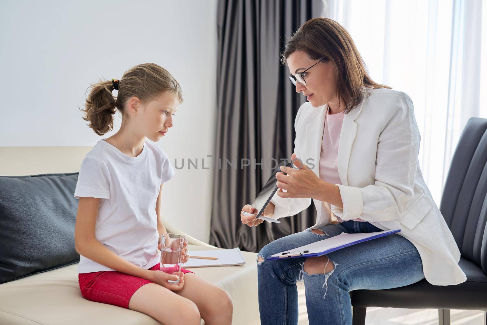 Woman social worker talking to girl at office. Child psychology, mental health, alternative therapy, psychotherapy