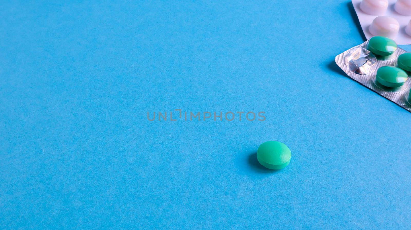 Two packs of pills and one round pill to the side on a blue background with copy space. antiviral tablets for pneumonia and bacterial infection. medicines and wellness treatments