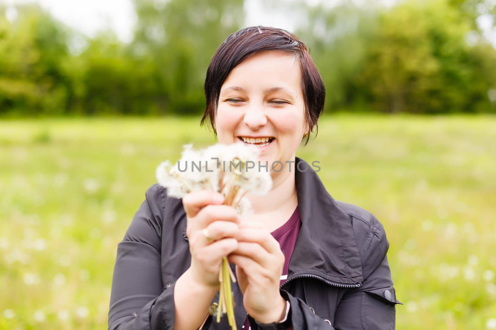 Girl blowing on white dandelion in the forest