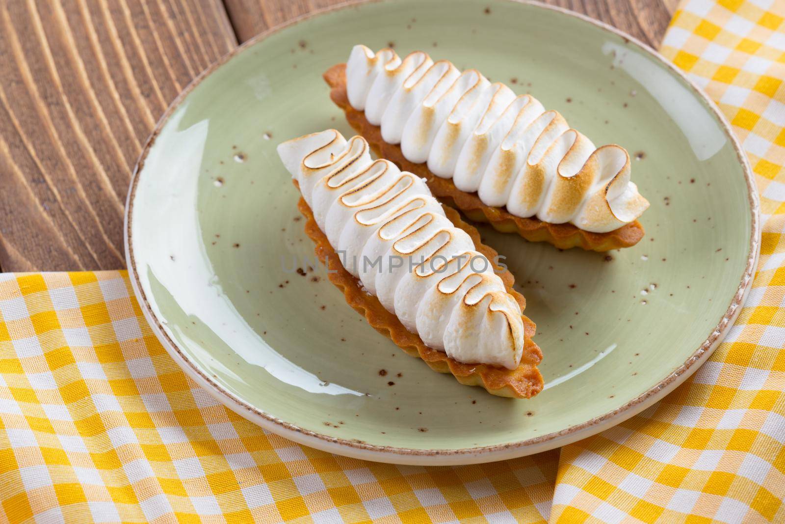Lemon tart with meringue on green plate close up