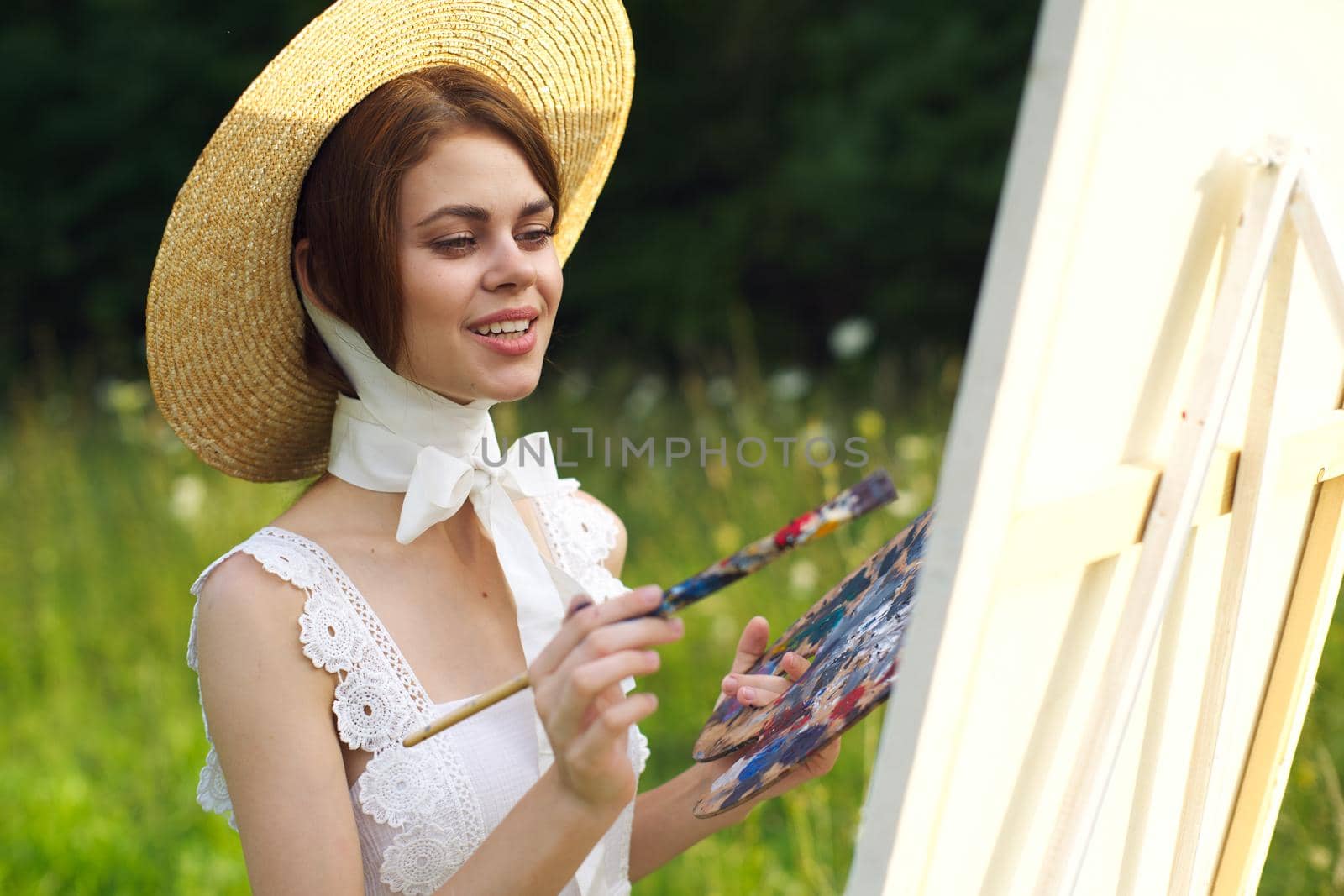 Woman in white dress artist paints on nature palette creative. High quality photo