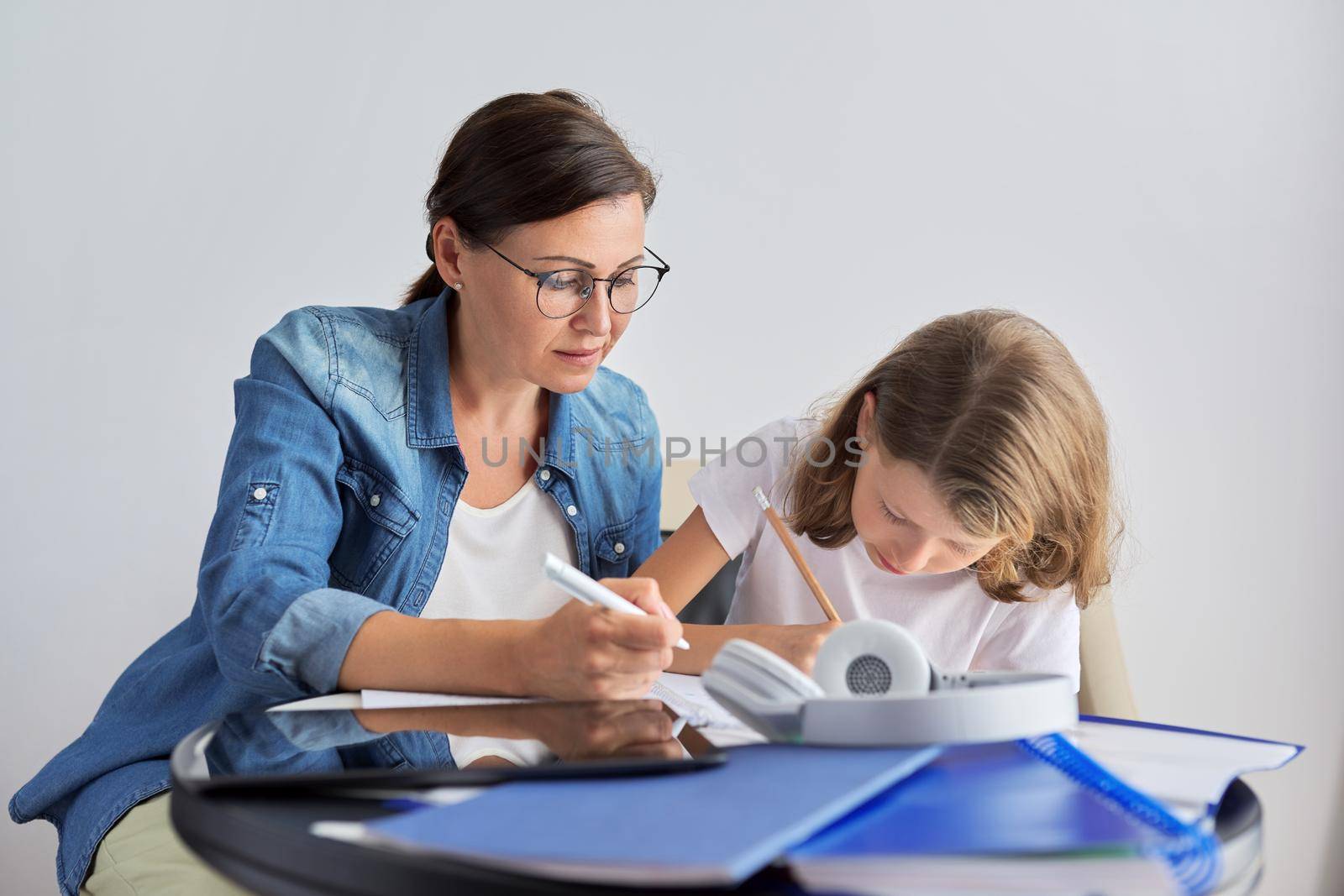 Mom and daughter student learning school lessons together at home by VH-studio