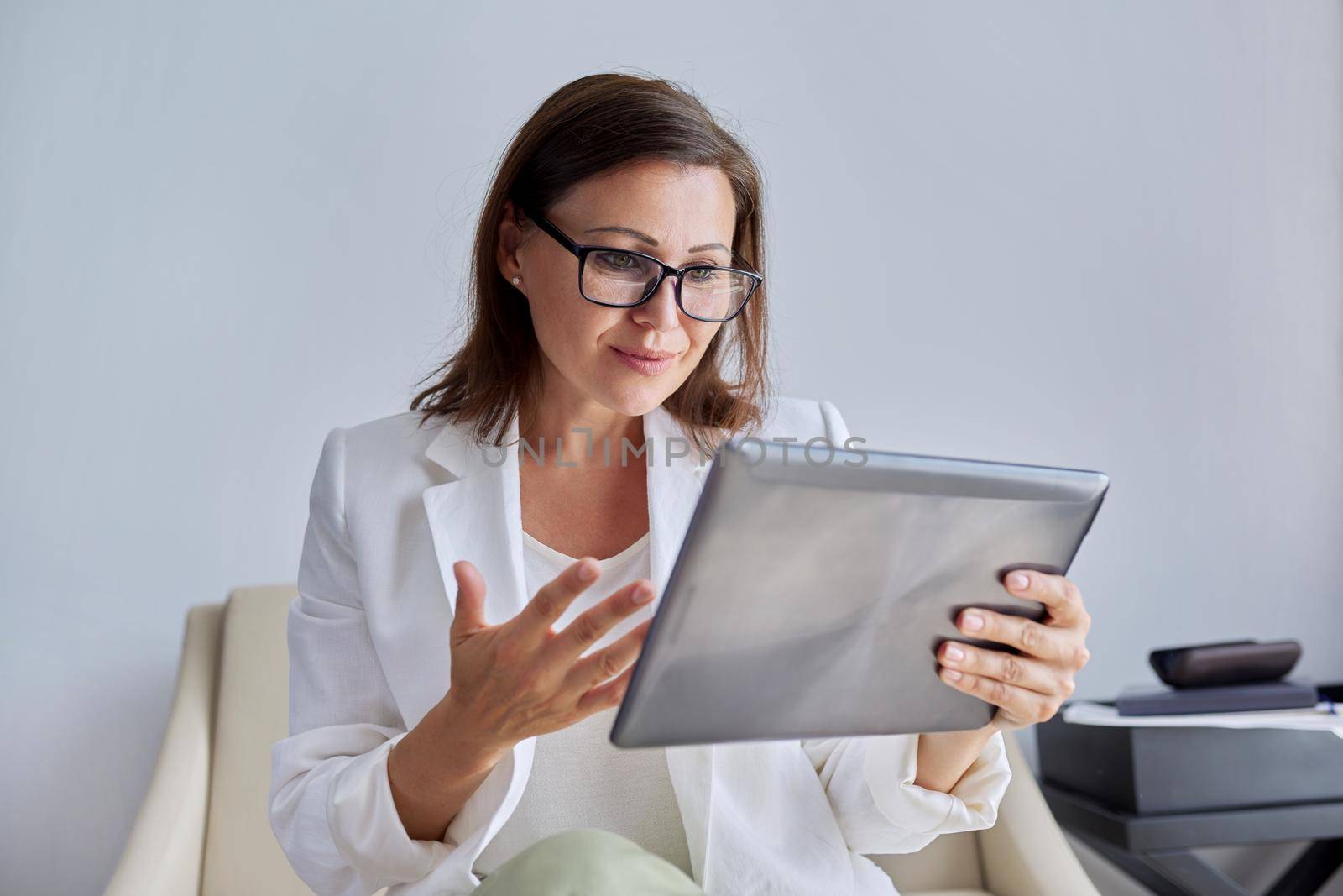 Talking businesswoman looking at screen of digital tablet by VH-studio