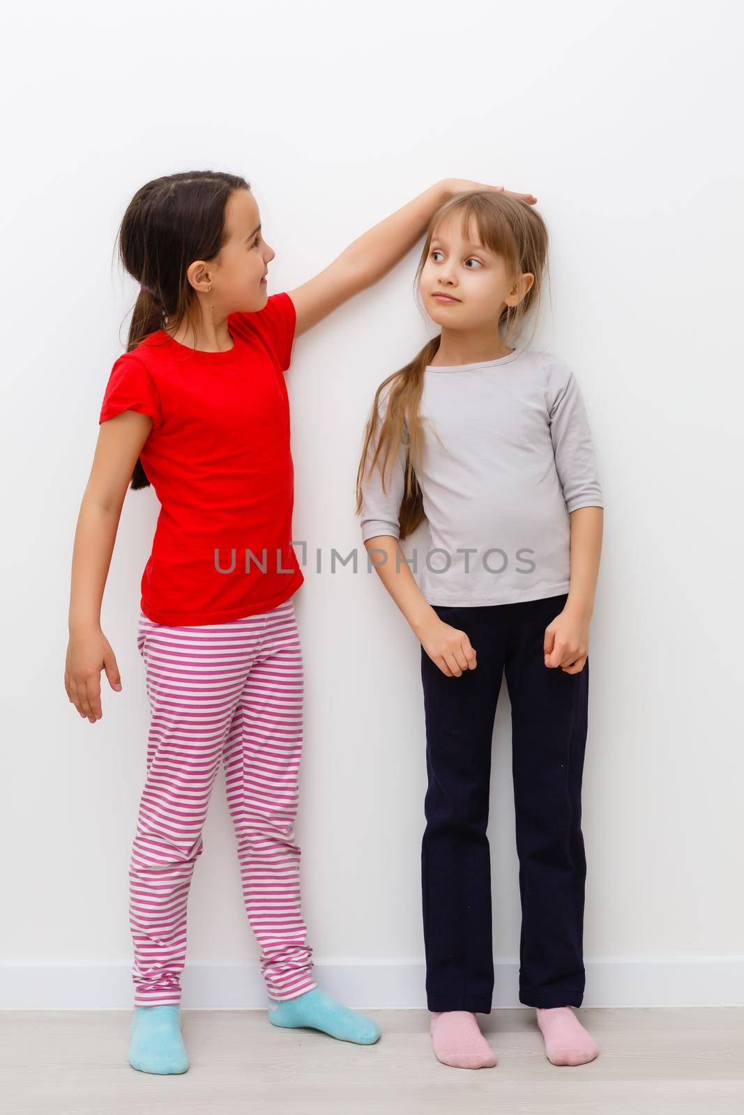 Two cute little girls in full growth, in the studio on a white background. The concept of a happy childhood, Beauty and fashion. Isolated.