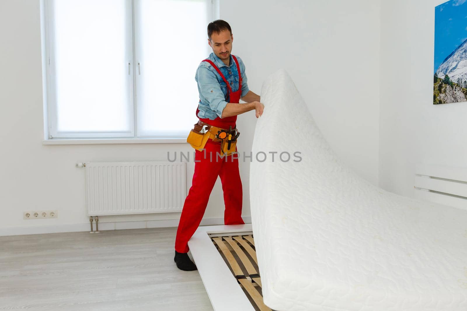 Man's hands working with a hex key. Assembling furniture. Wooden plank of a bed. Close up.