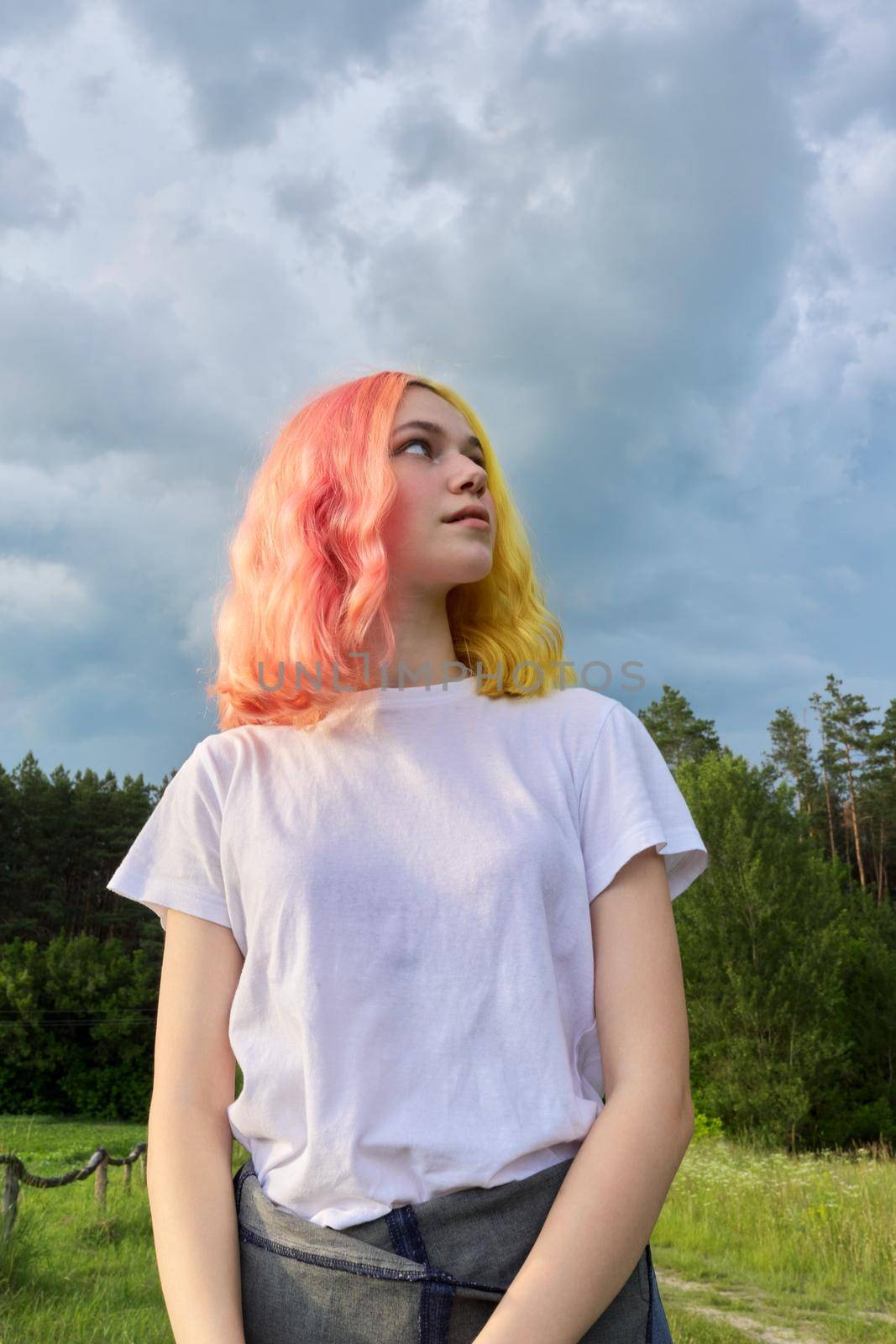Portrait of a teenage girl hipster 15, 16 years old with dyed hair, dramatic sky nature background