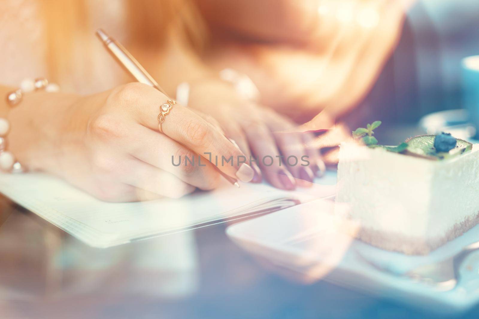 Woman making notes while sitting in a coffee shop. Close up.