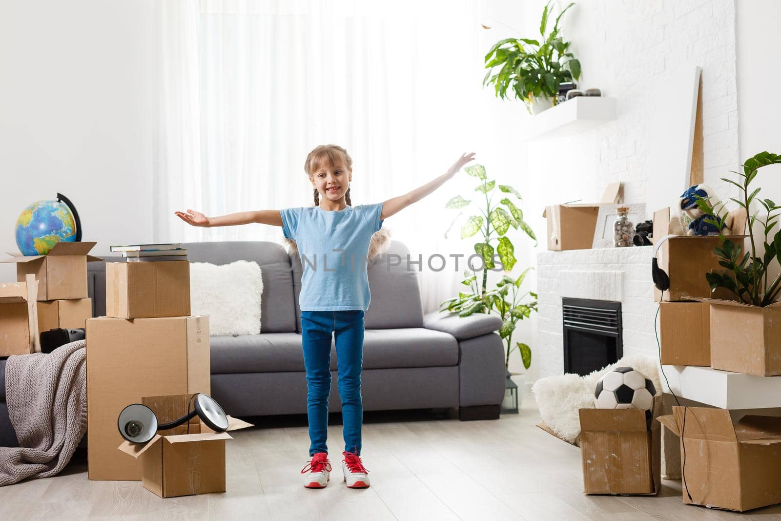 Little girl moving into new house, near cardboard box.