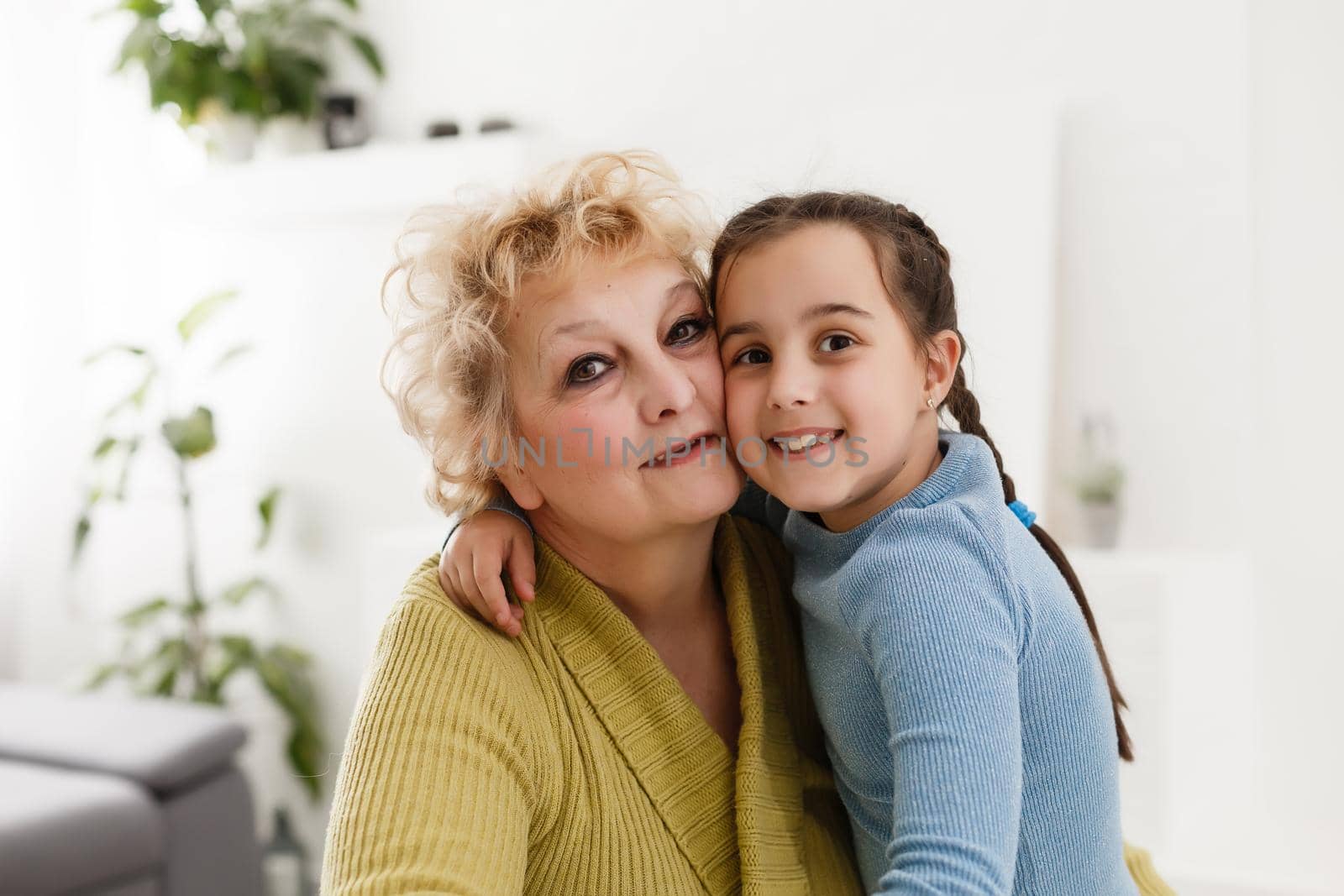 Portrait of happy old grandmother and kid girl looking at camera, smiling grandma with granddaughter making video call, child and granny vloggers recording video blog or vlog together