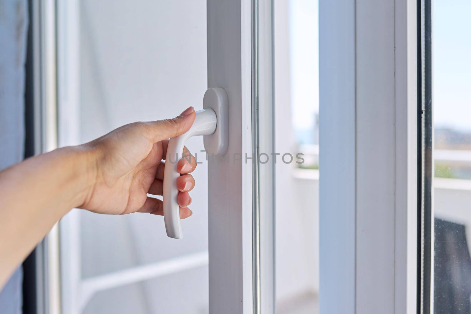 Close-up of hand opening glass balcony block door.