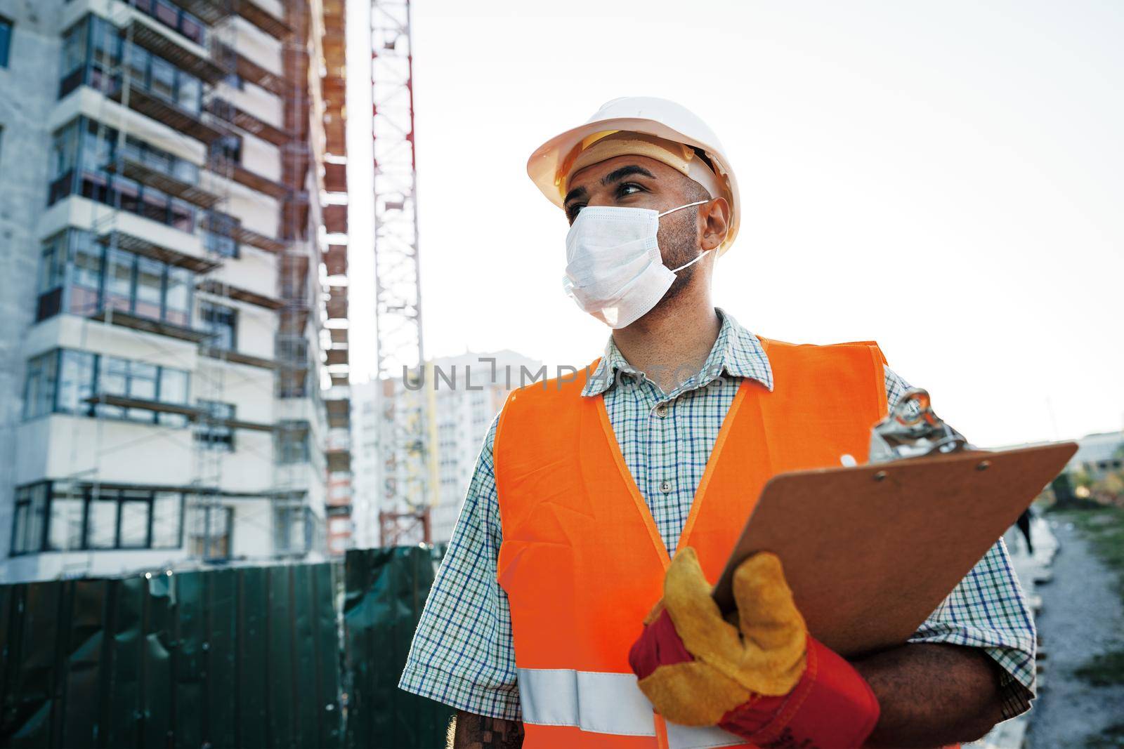 Foreman at work on construction site checking his notes on clipboard, close up