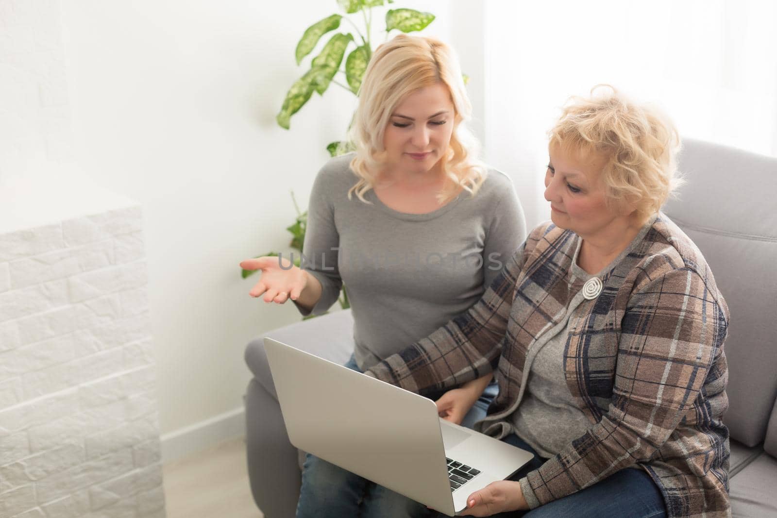 Cheerful elderly woman and smiling girl choosing purchases online. Focus on mature