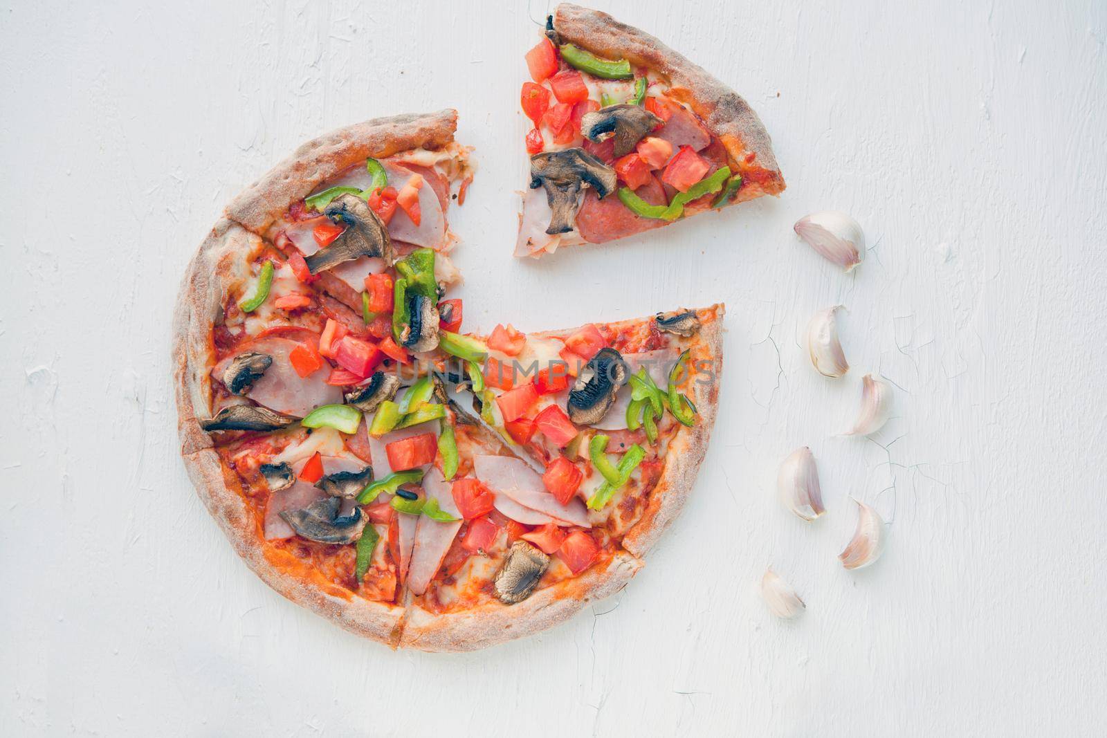 Top view of Italian Pizza on white table with mushrooms, tomato, olives and cheese. Look as Prosciutto, Capricciosa, PIZZA with decoration. Photo with space for text.