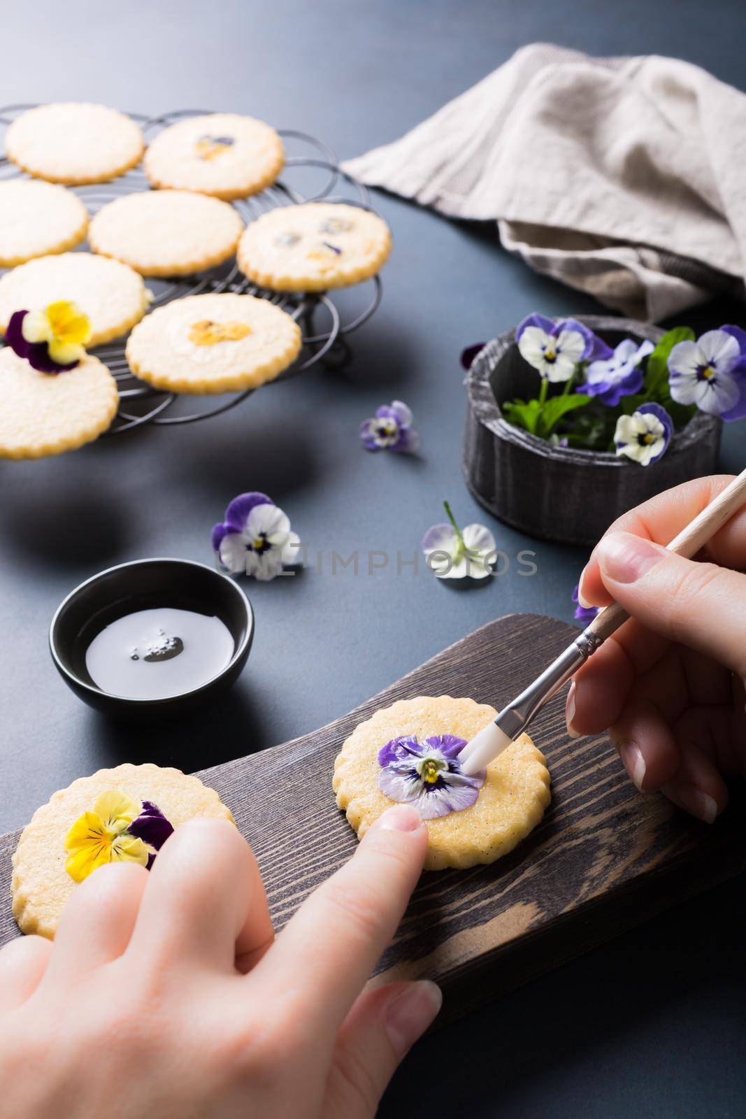 Process of making shortbread cookies with edible flowers on old wooden background. Holiday food