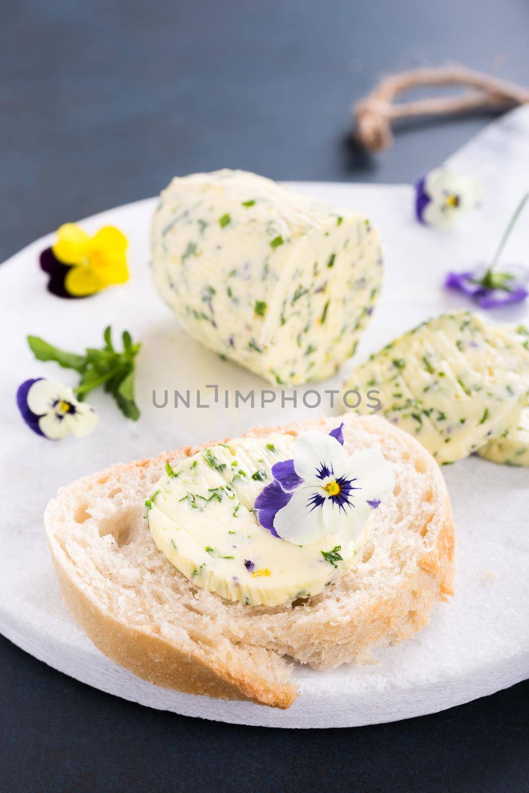 Sandwich with herb and edible flowers butter on marble cutting board. Healthy food.