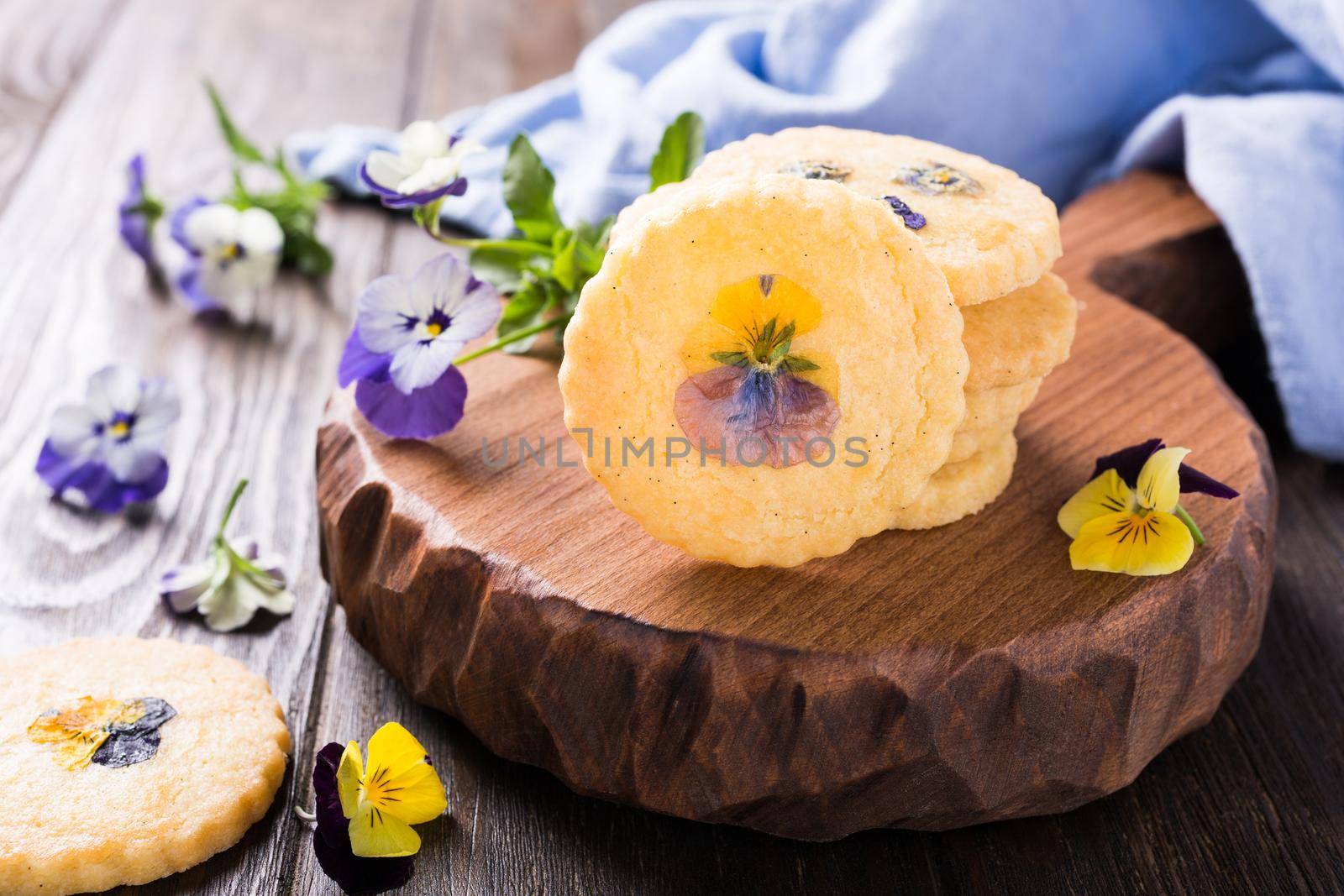 Homemade shortbread cookies with edible flowers on old wooden background. Holiday food