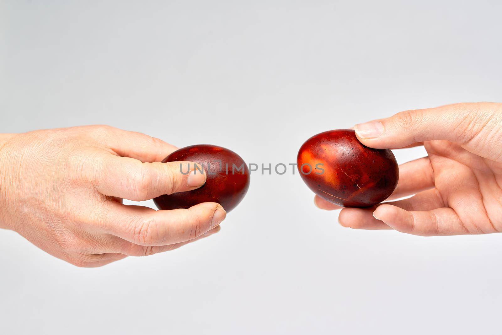 Two hands holding Easter eggs check their strength on a light background by vizland