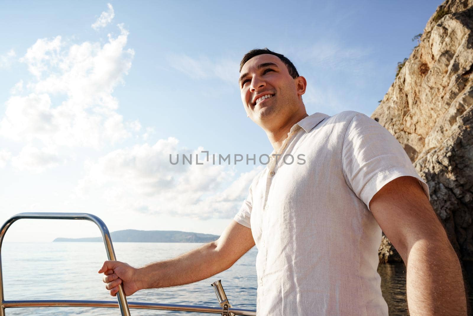 Young man in white shirt standing on the nose yacht in the open sea