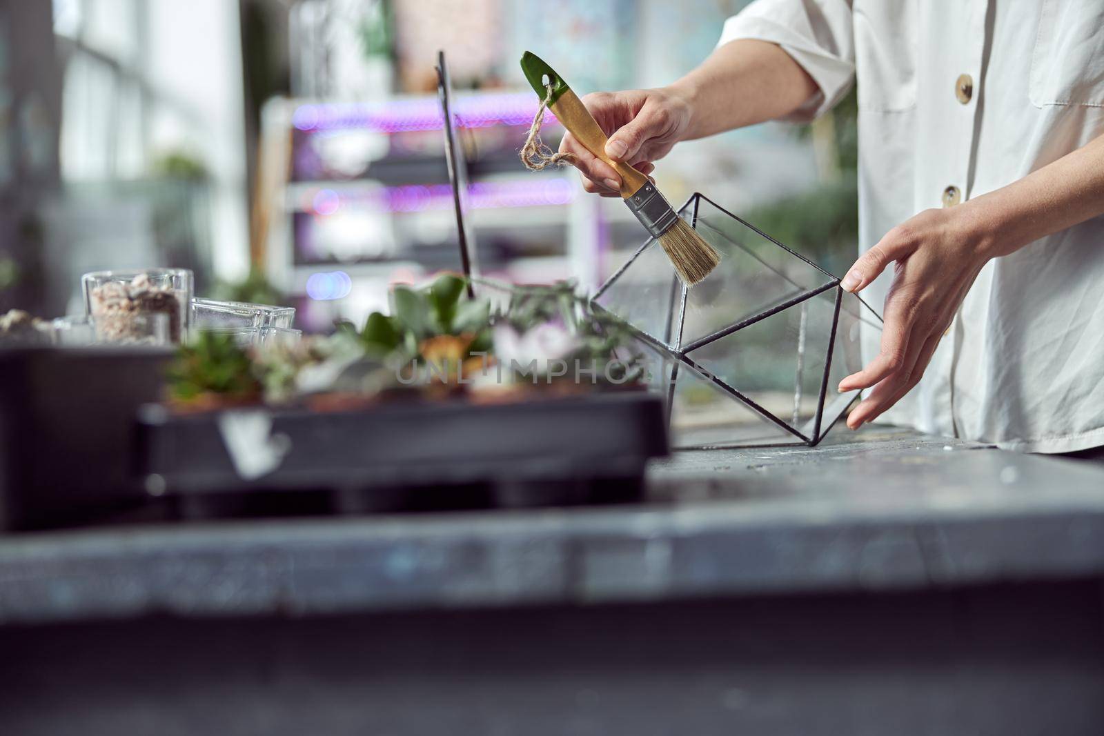 caucasian confident happy florist is working with composition made from glass stones and plants in botanic shop