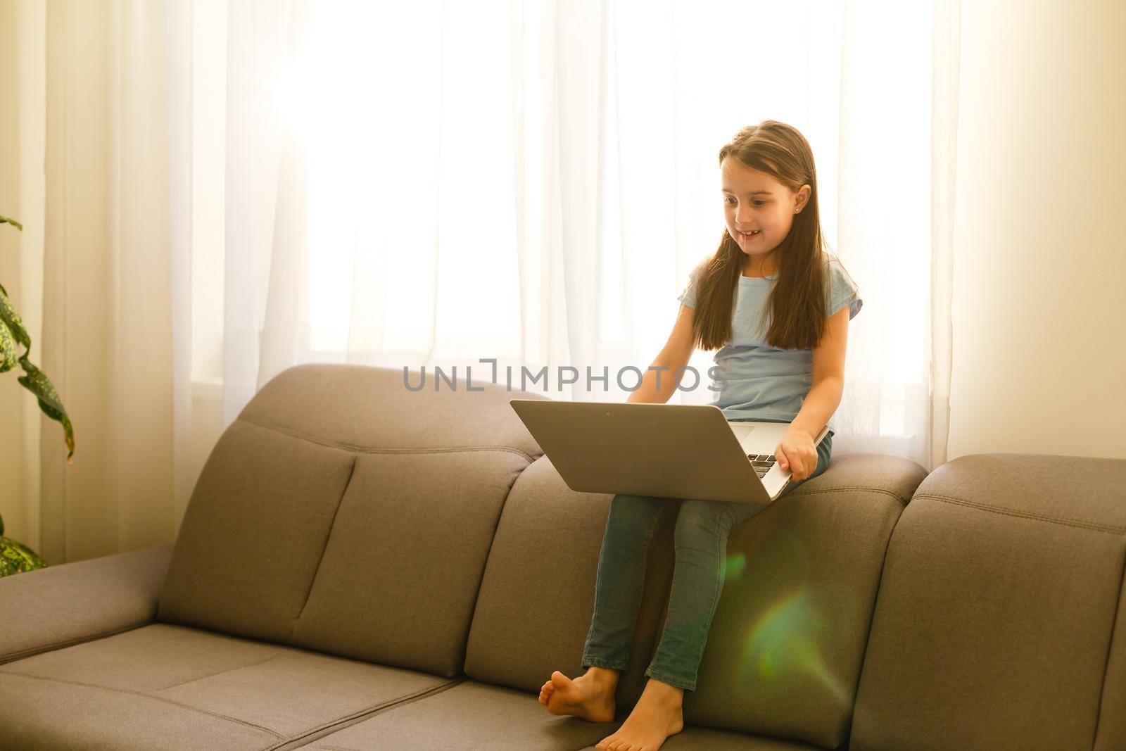 Remote lessons. The child smiles happily and gets knowledge remotely. Little girl study online learning from home with laptop. Online school.