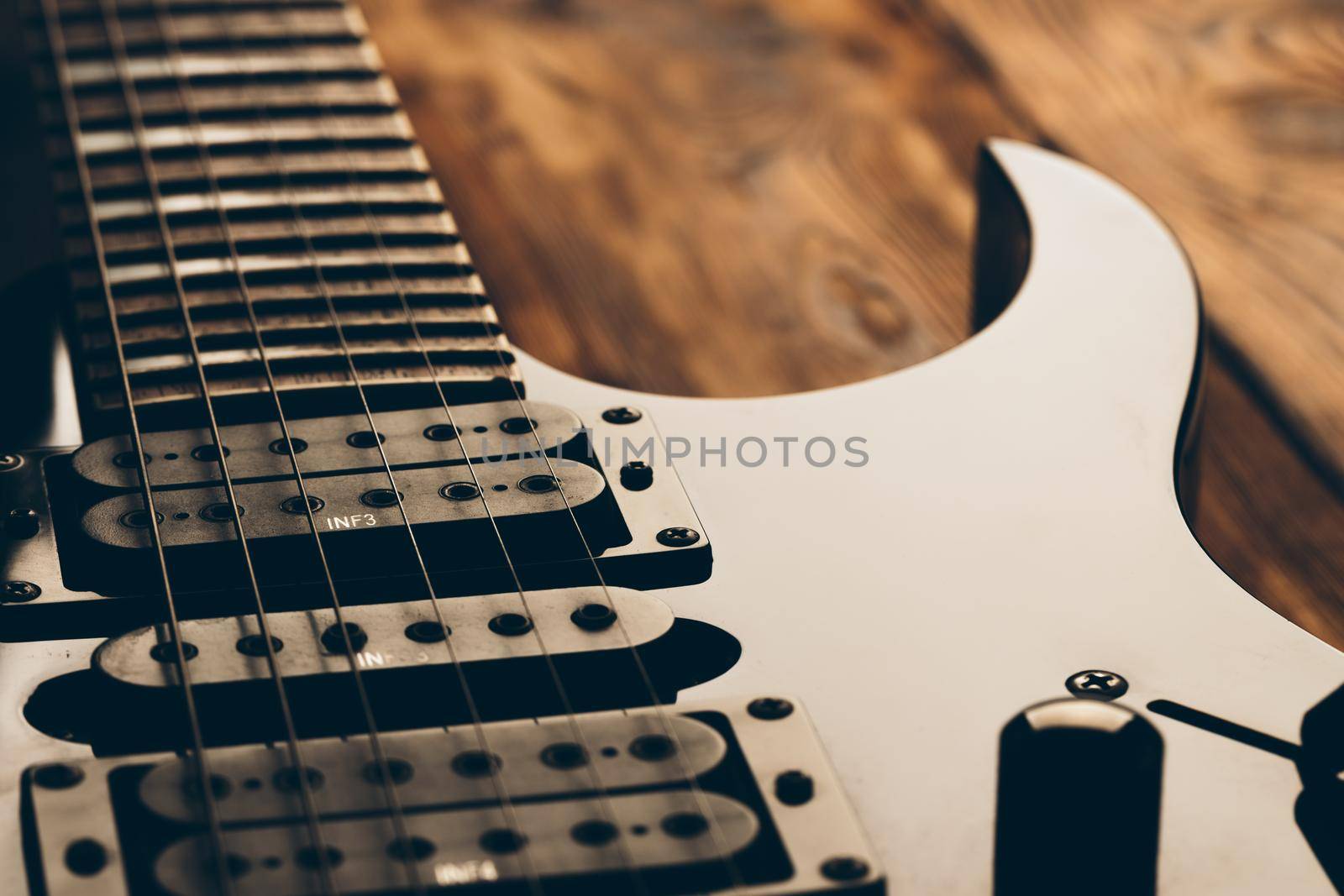 Close up photo of electric guitar fingerboard on dark background