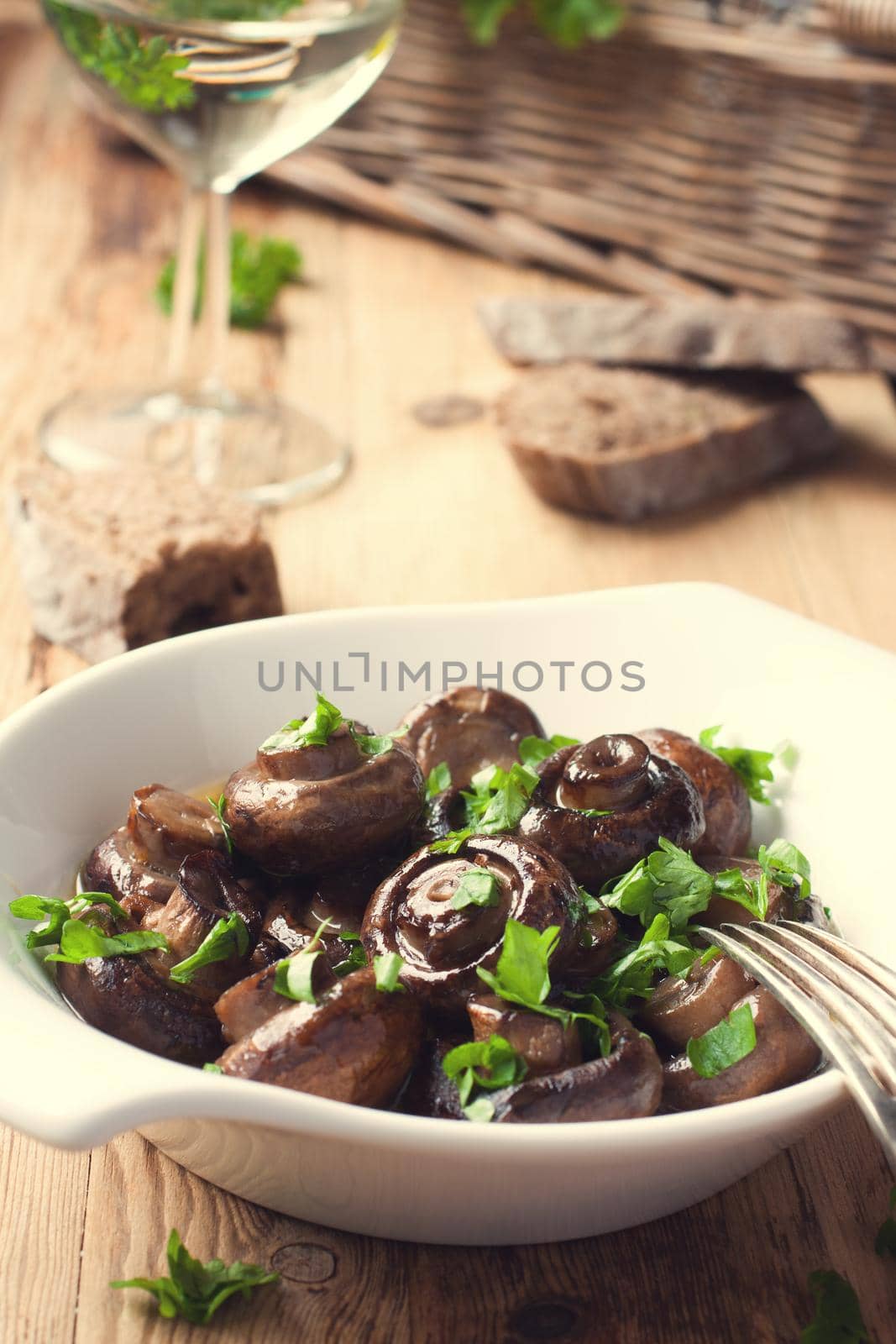 Baked champignons mushrooms with butter, parsley and roasted garlic in white bowl. Selective focus. Healthy food concept. Toned photo.