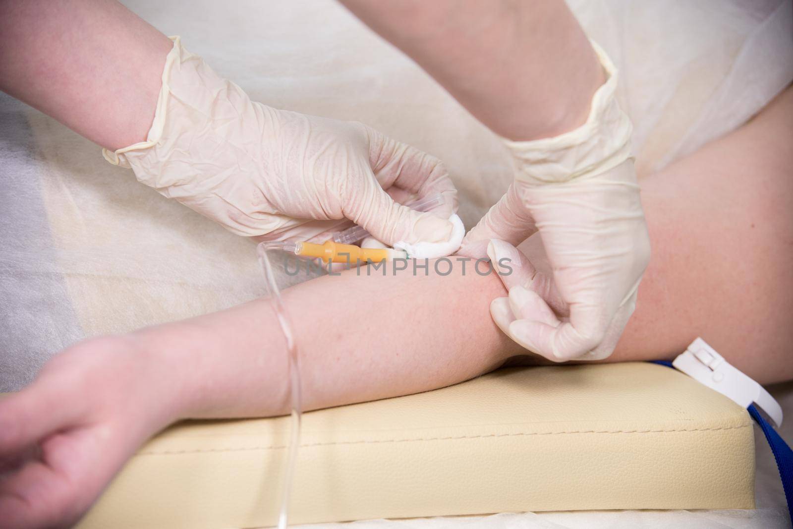 A nurse in gloves taking a blood sample from a hand for testing. Mid shot