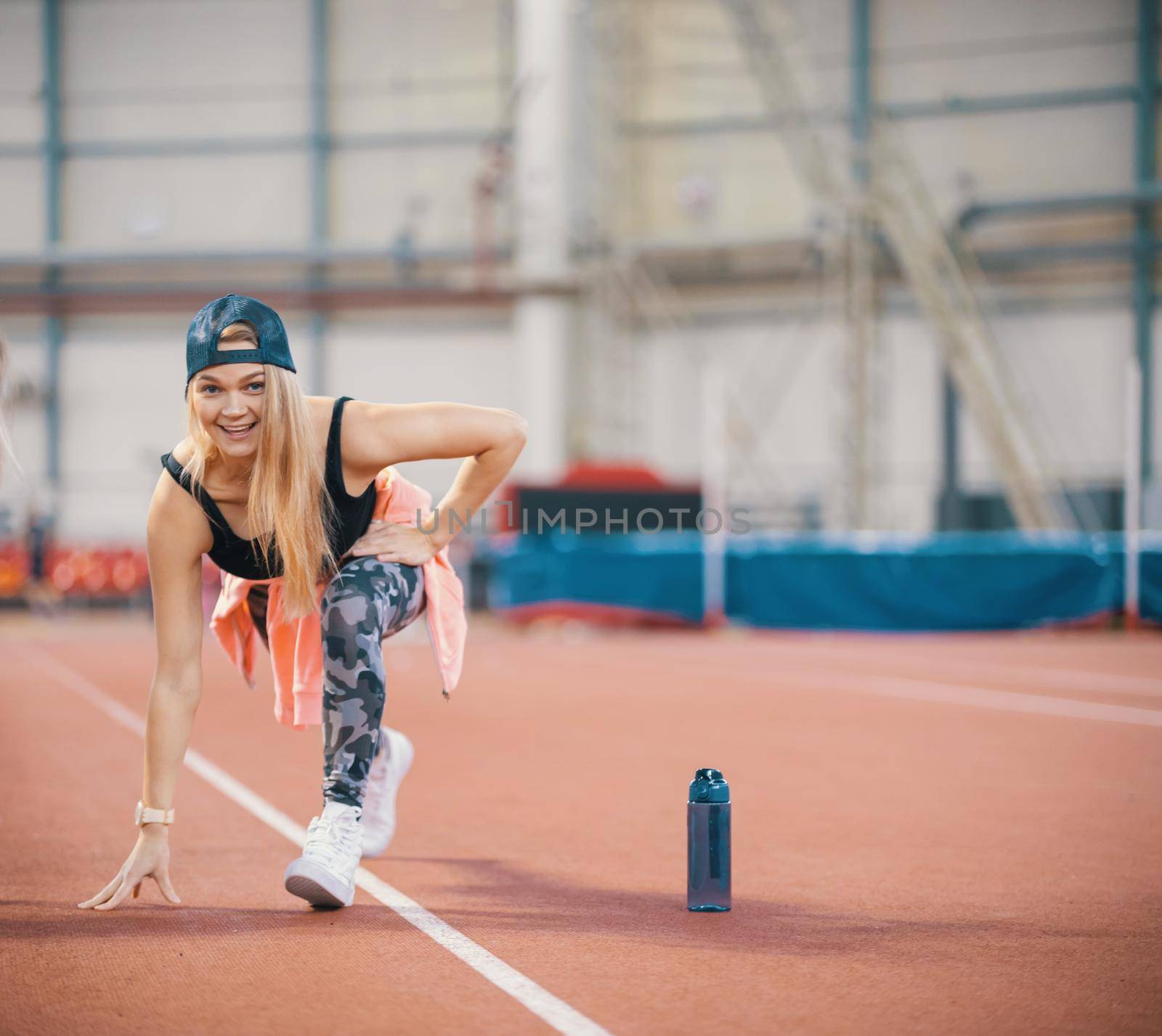 Young fit athletic woman warming up. Looking in the camera. Mid shot