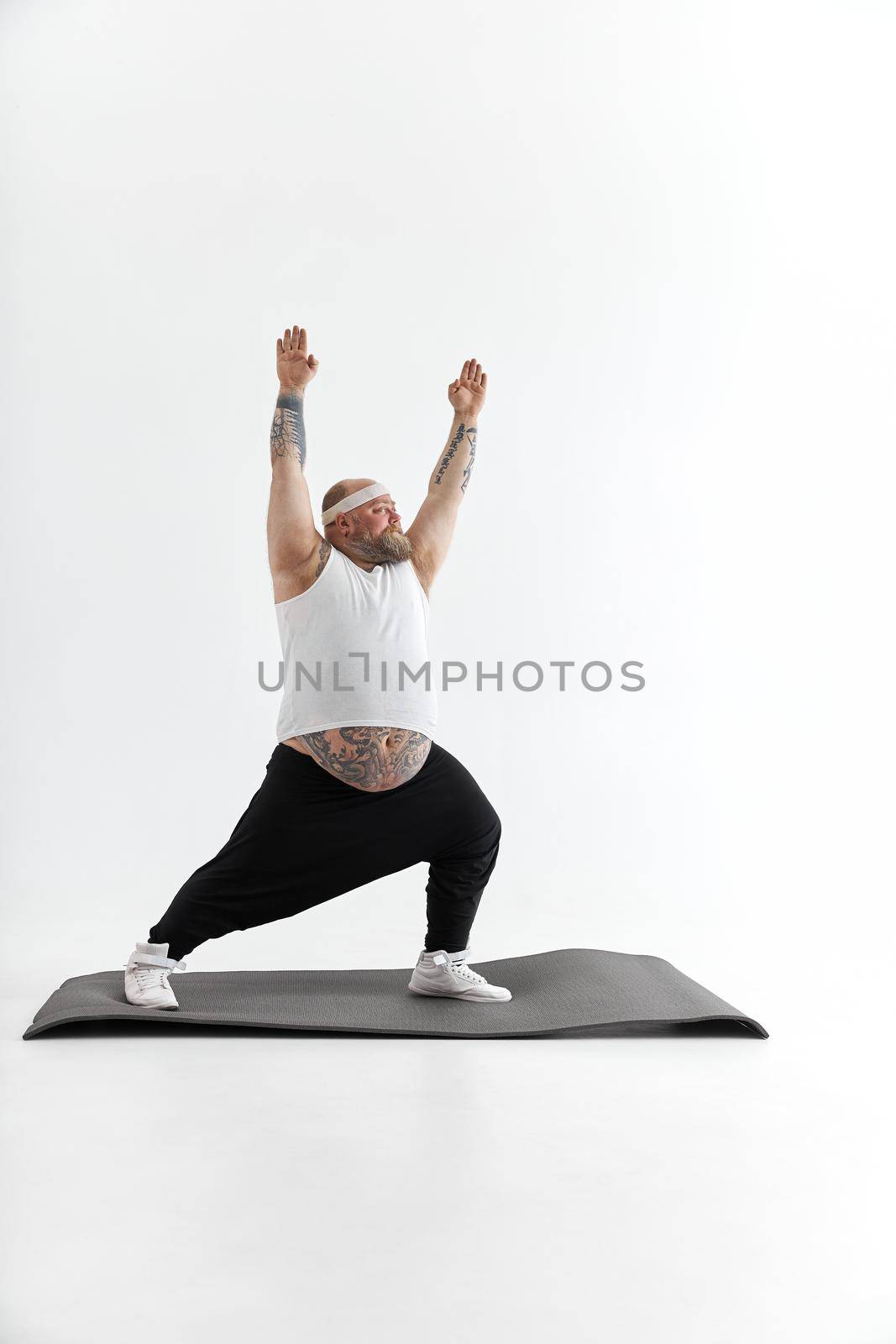 Sporty fat man with beard and tattoos is doing yoga by Yaroslav_astakhov